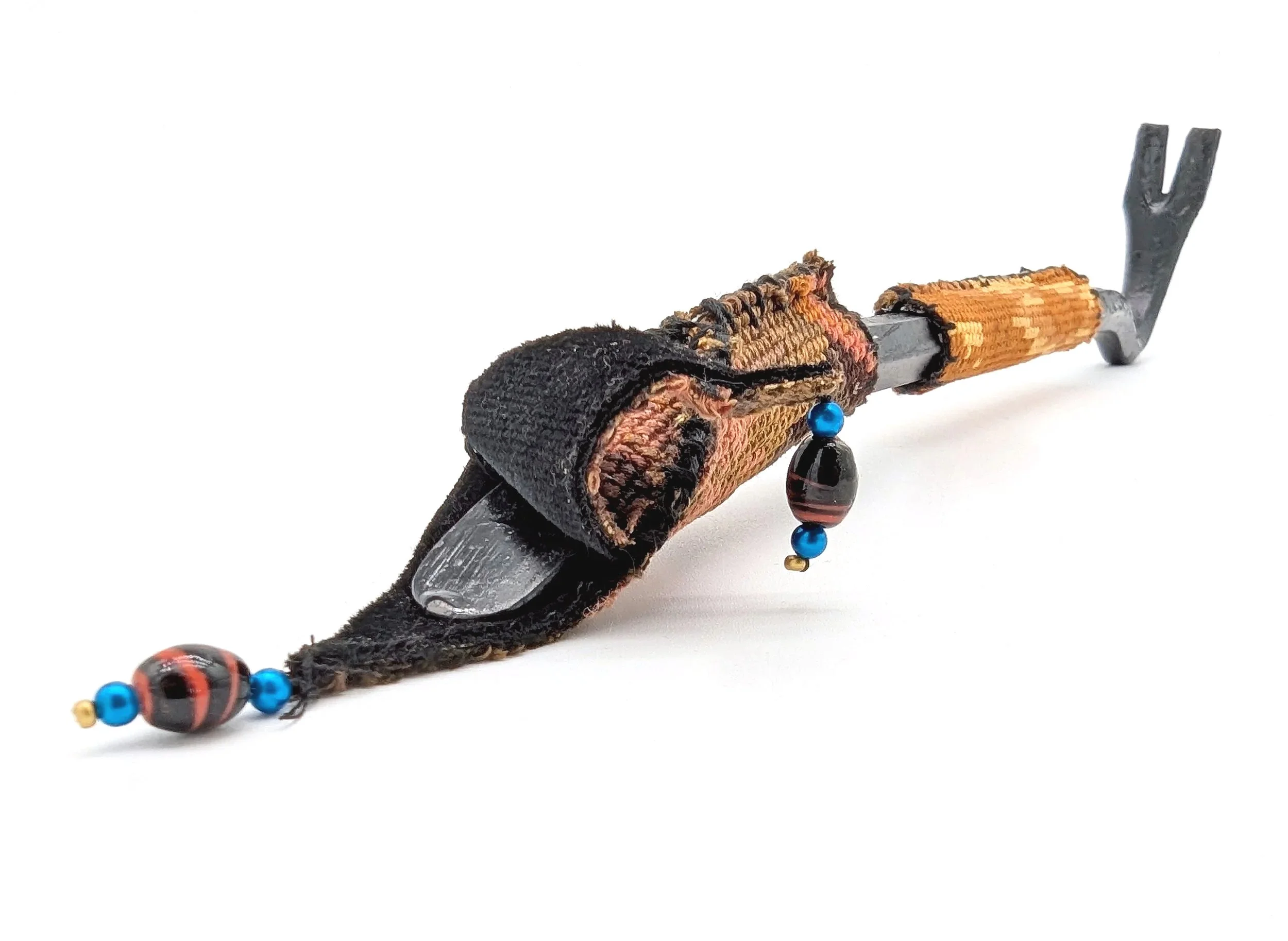 A small black crowbar, decorated with colorful beads, wrapped in a cross stitch of the Rembrandt painting The Night Watch.