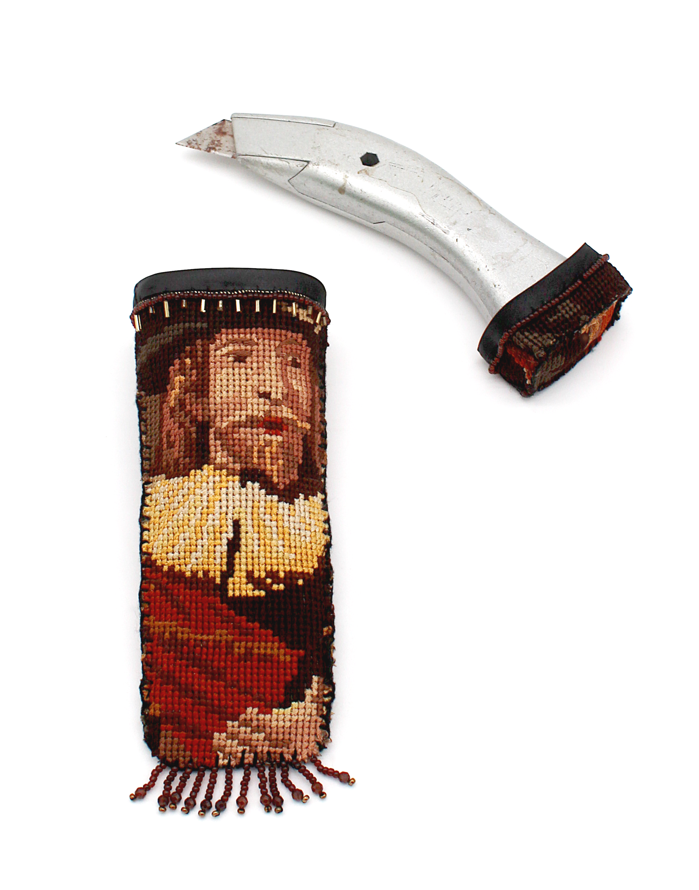 A boxcutter with a belt holder that have been wrapped in a cross-stitch of the Rembrandt painting The Night's Watch and covered in brown beading and bead fringe.