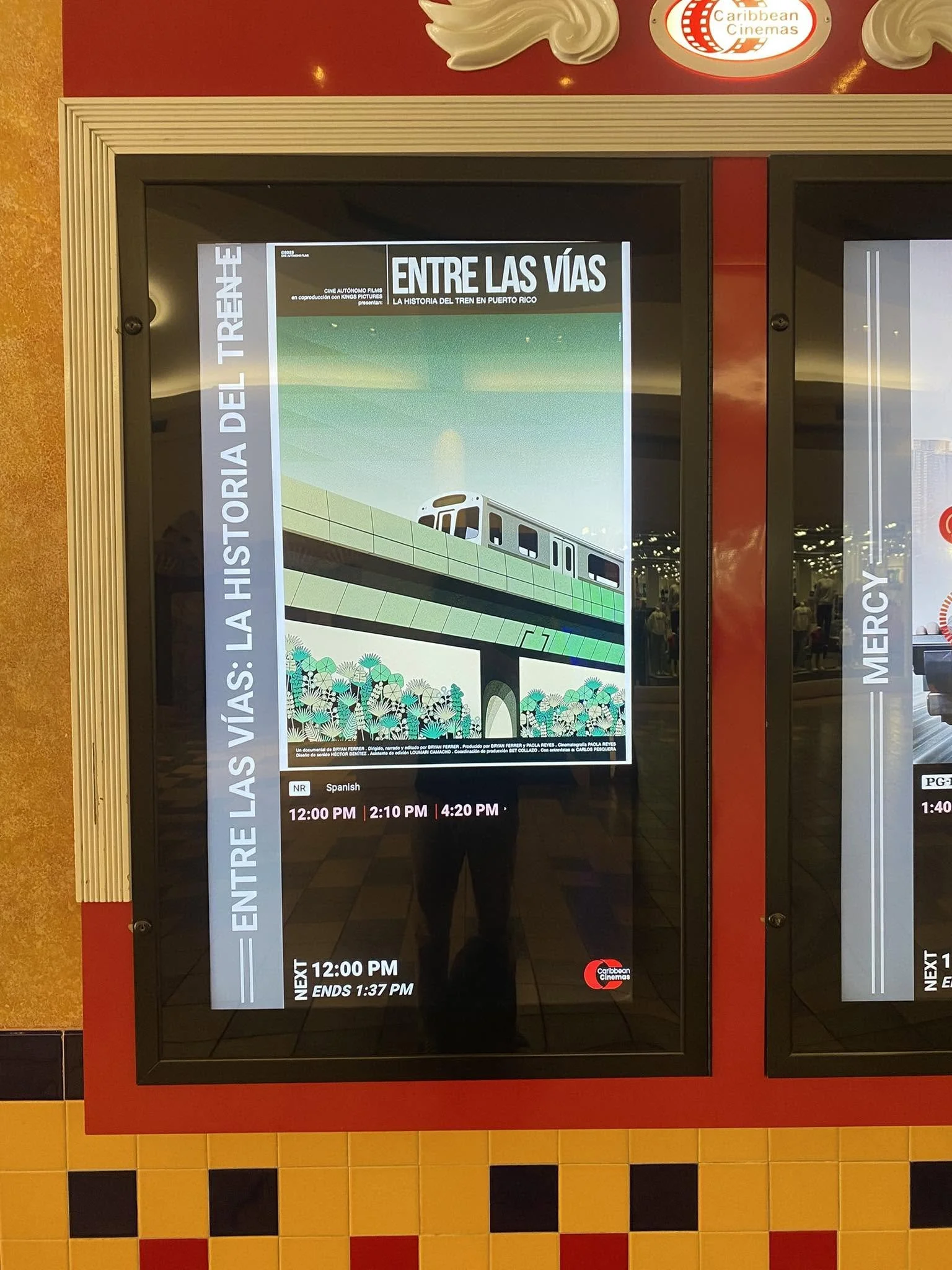 Cartel de información en un cine que muestra los horarios de una película titulada 'Entre las vías'.