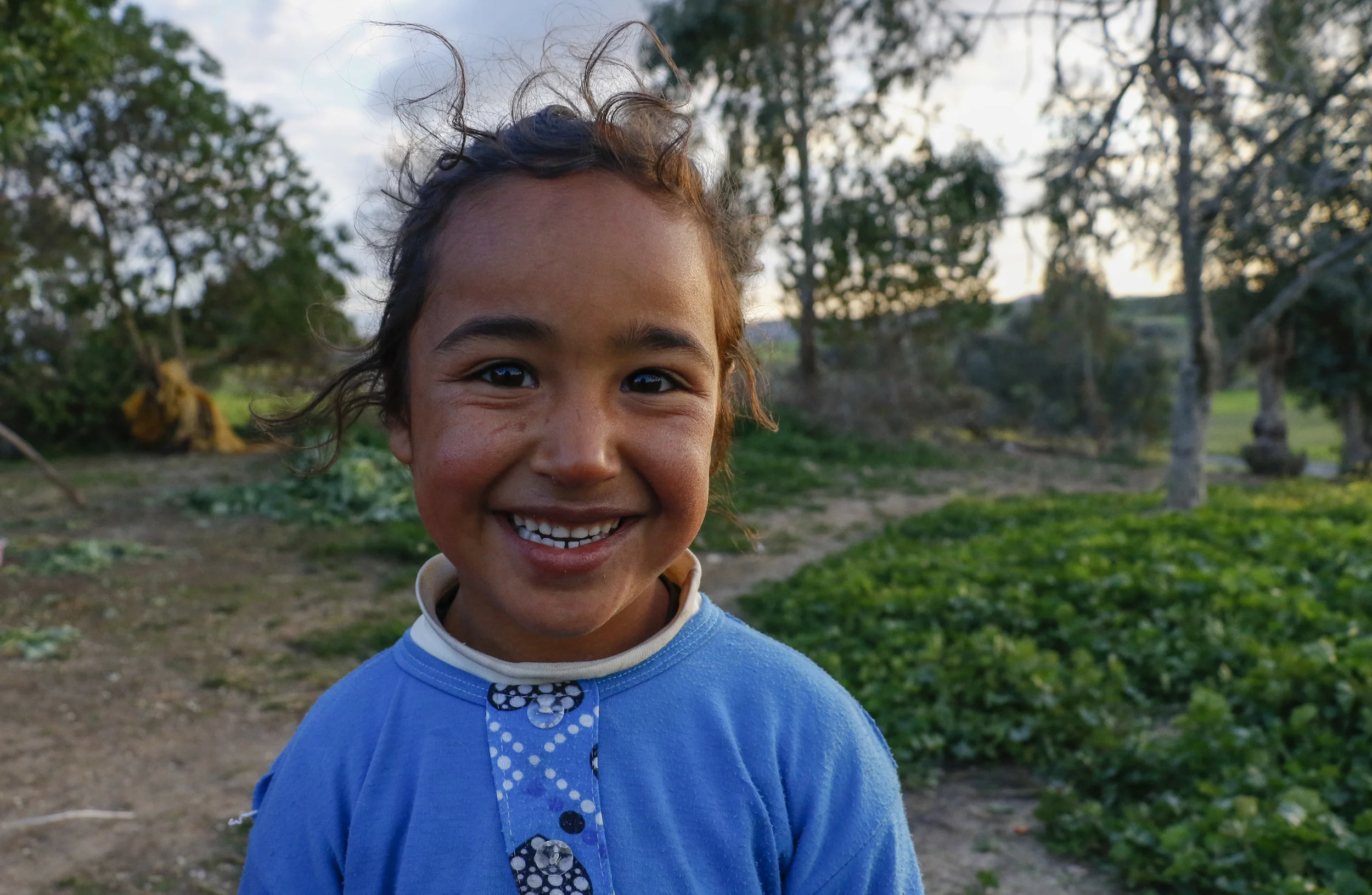 Farah, 8, is Hana's oldest child. She often stayed in her yard, waiting to be invited to play in other children's activities. Here, she poses for a photograph as her mother harvest Moroccan spinach.