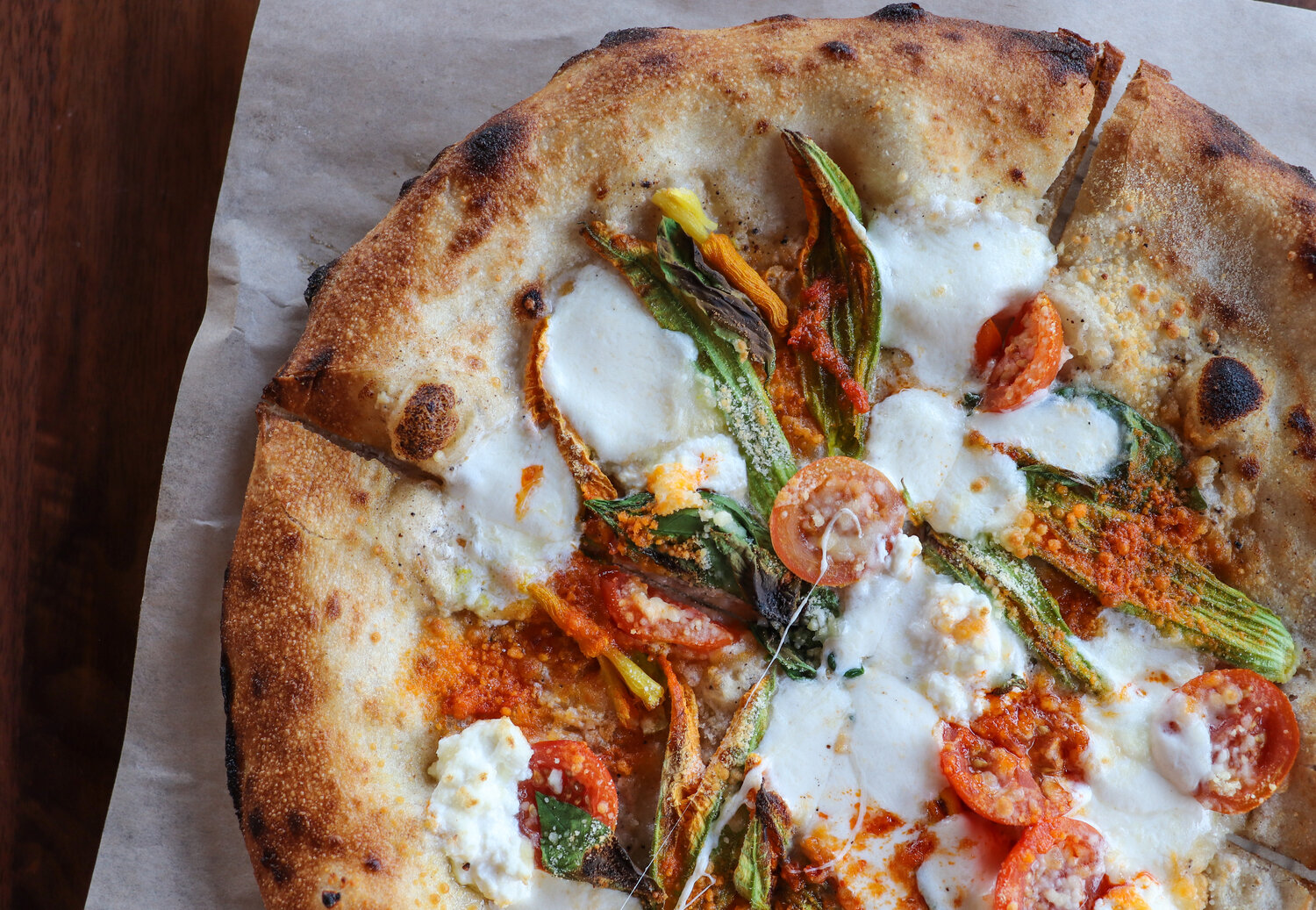 Fresh out the oven! Neapolitan inspired pizza with squash blossoms, heirloom tomatoes, Calabrian chilis, and smoked ricotta.