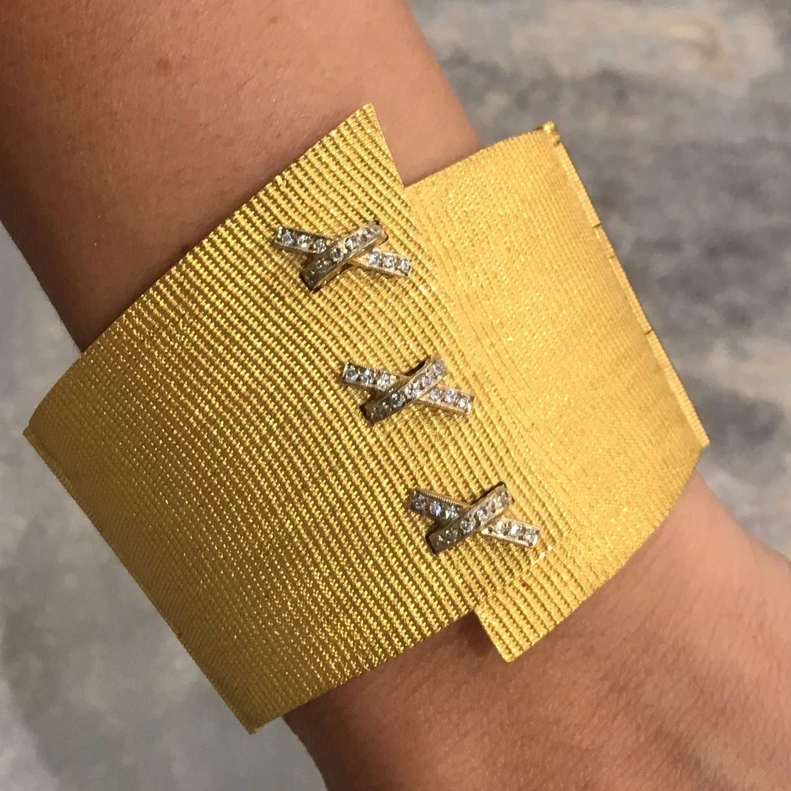 Lina Fanourakis Button Holes Cuff. A finely plated cuff of 18K yellow gold has three tiny diamond and white gold bowties.
