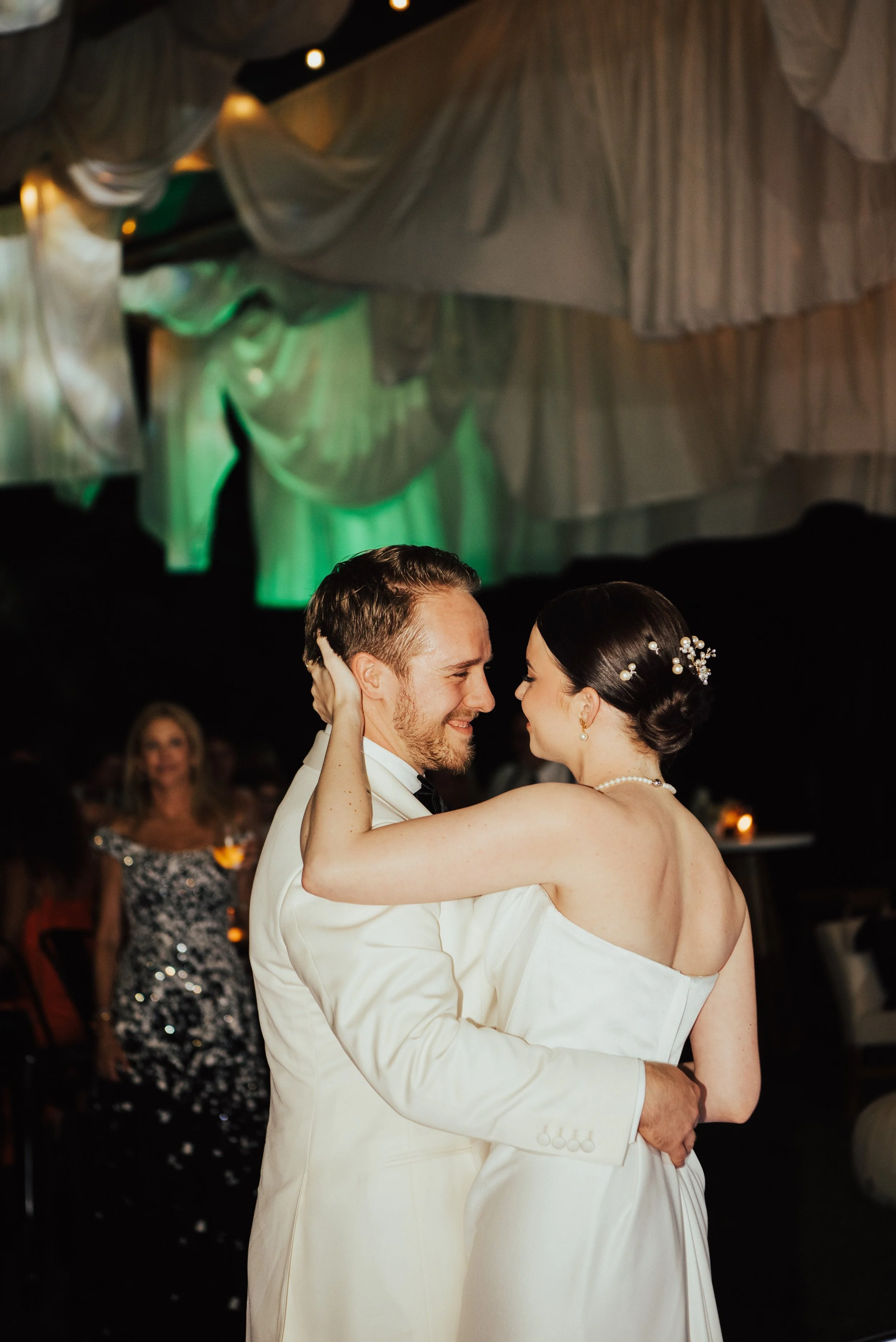 close up of bride and groom smiling at each other as they dance.