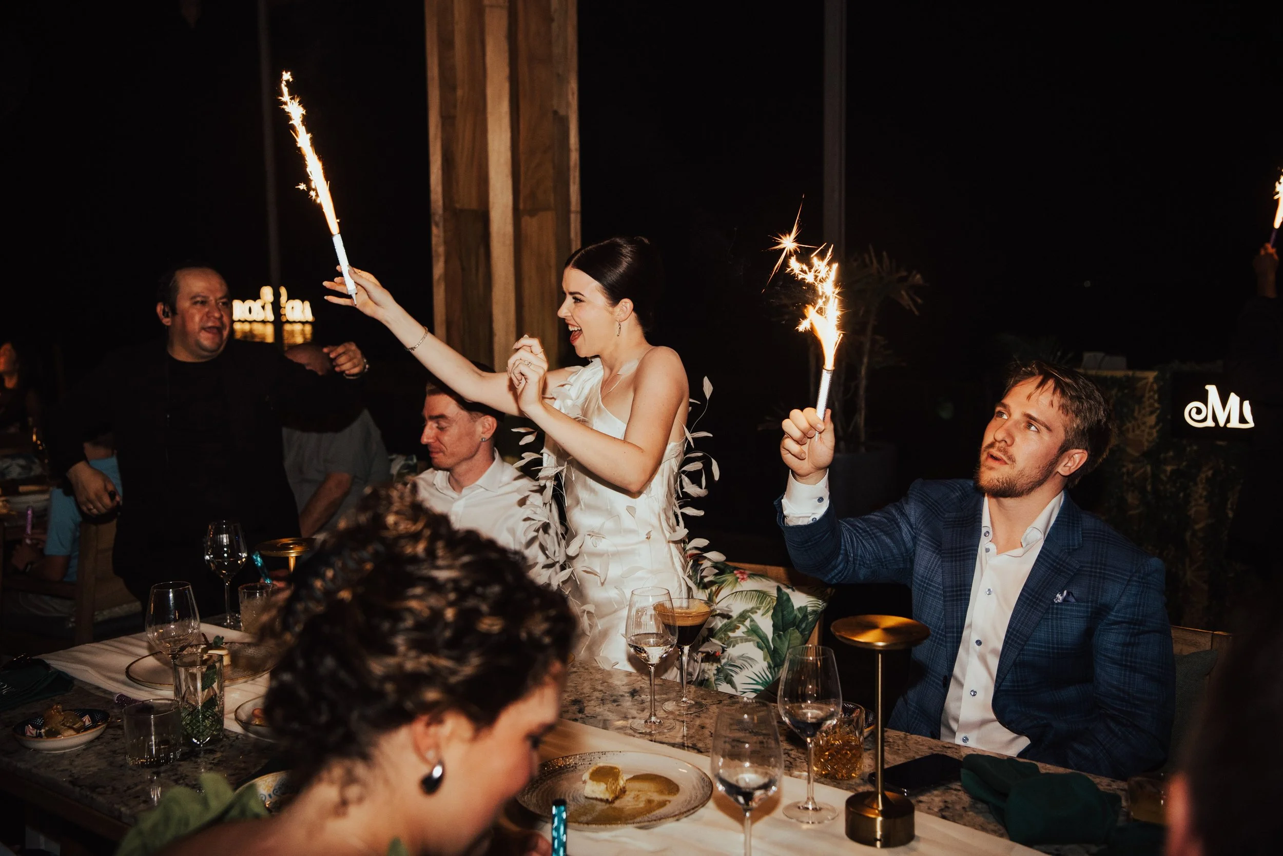 bride and groom holding sparklers at their rehearsal dinner table