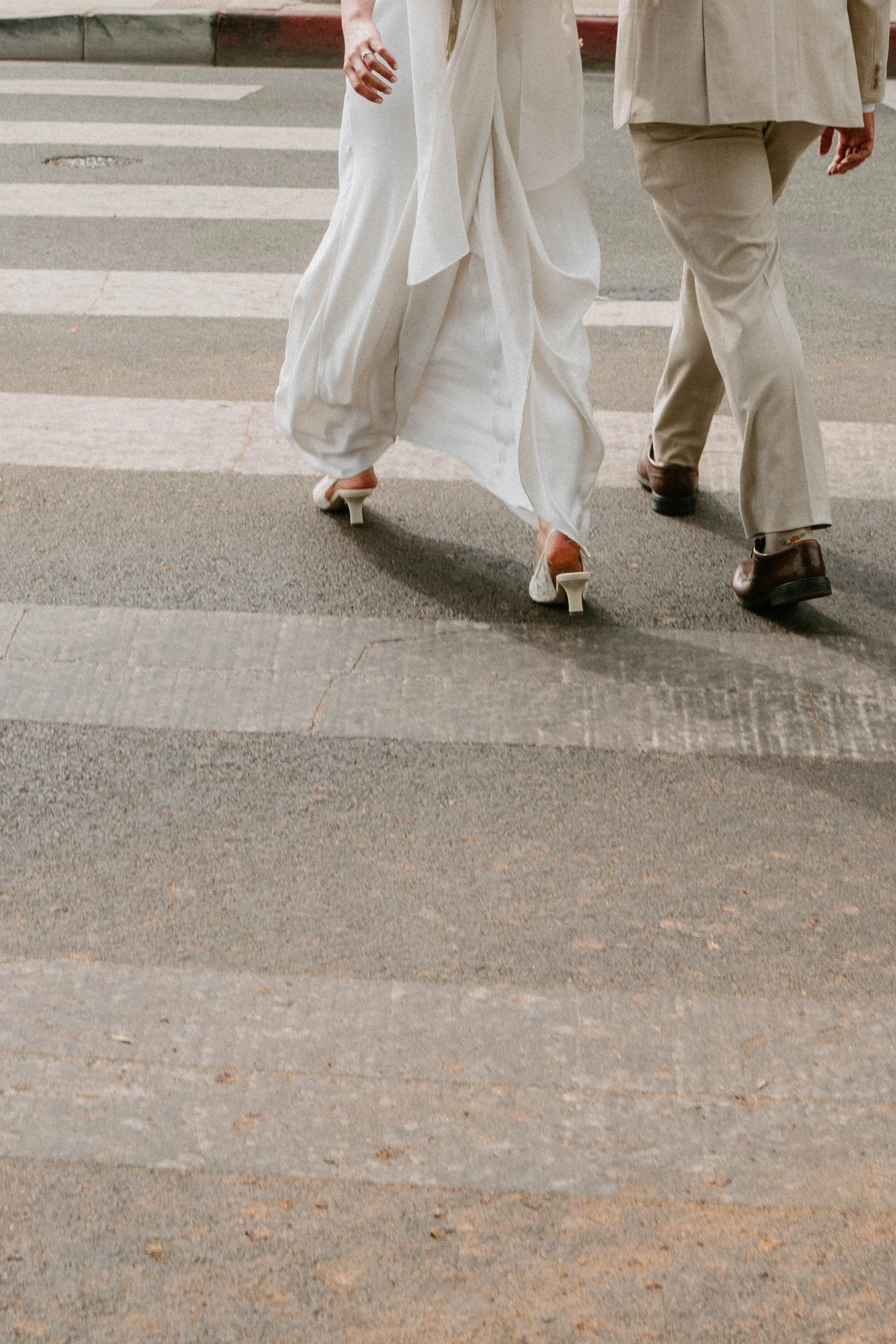 close up photo of bride and grooms feet as they walk across the crosswalk