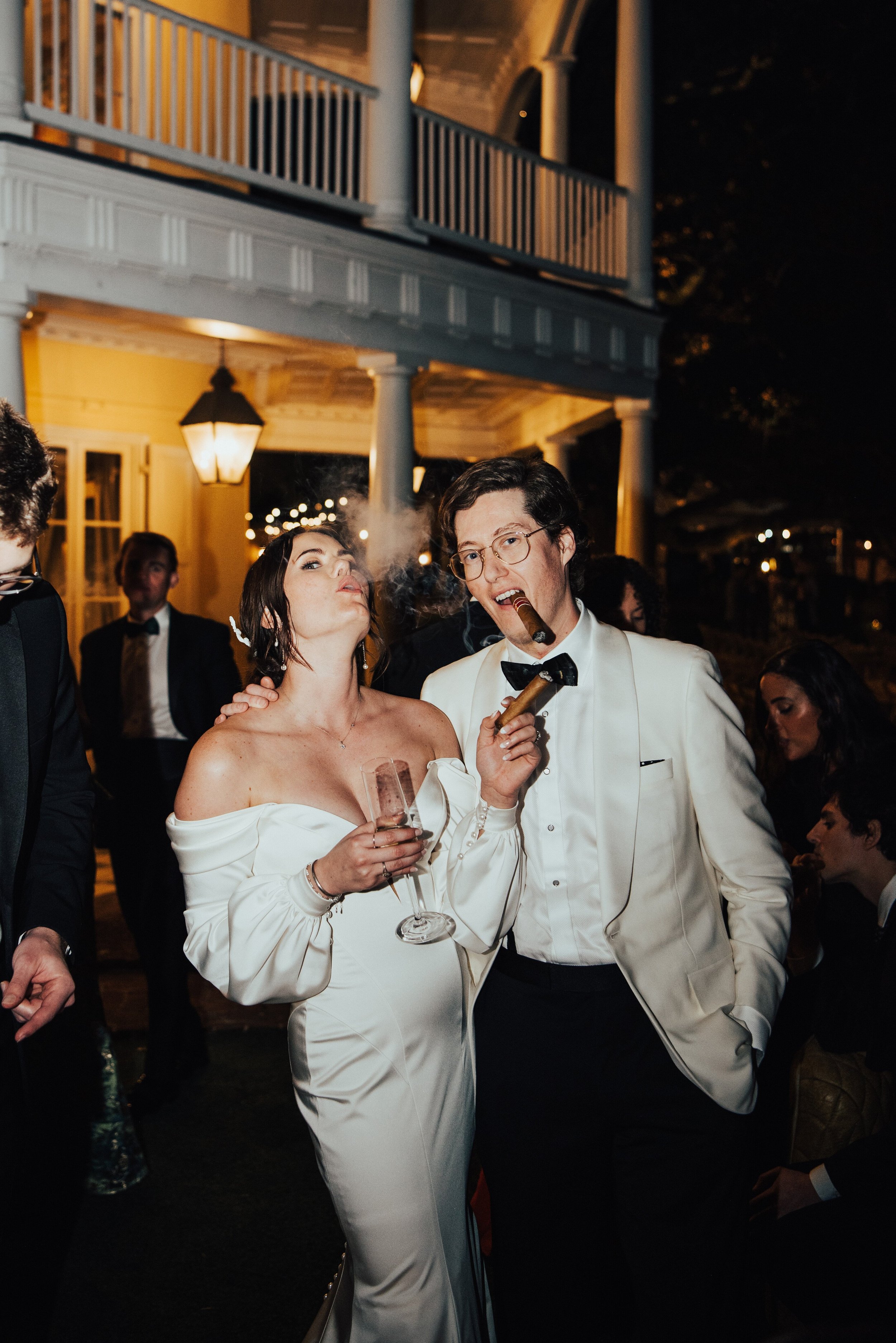 bride and groom smoking cigars while facing the camera.