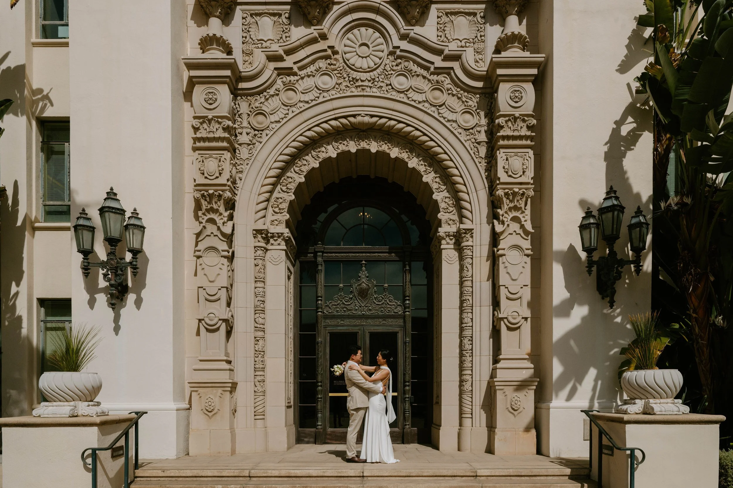 Bride and groom embracing in front of the arched door way of the Beverly Hills city Hall