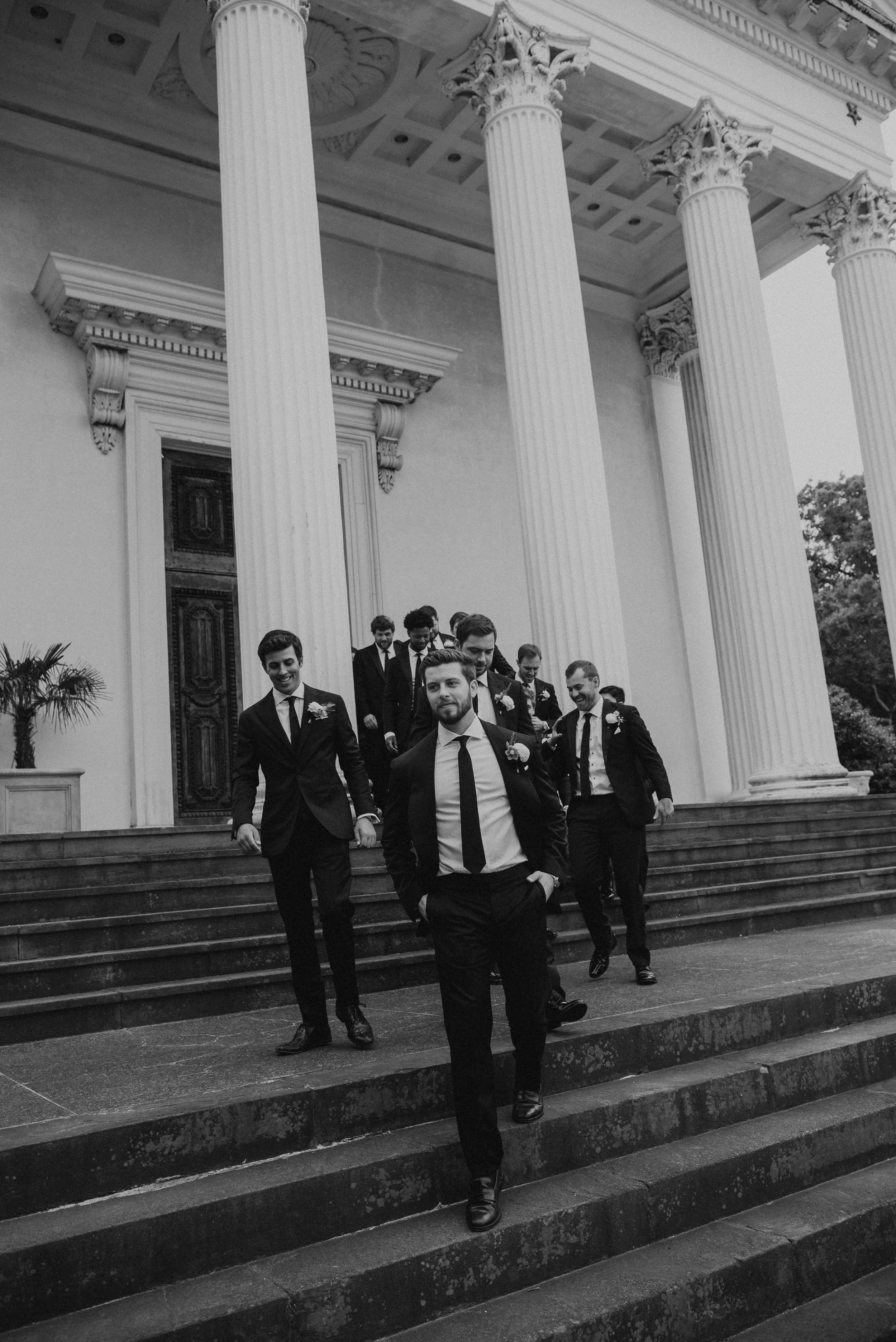 Black and white photos of Groom and groomsmen walking down the step of church