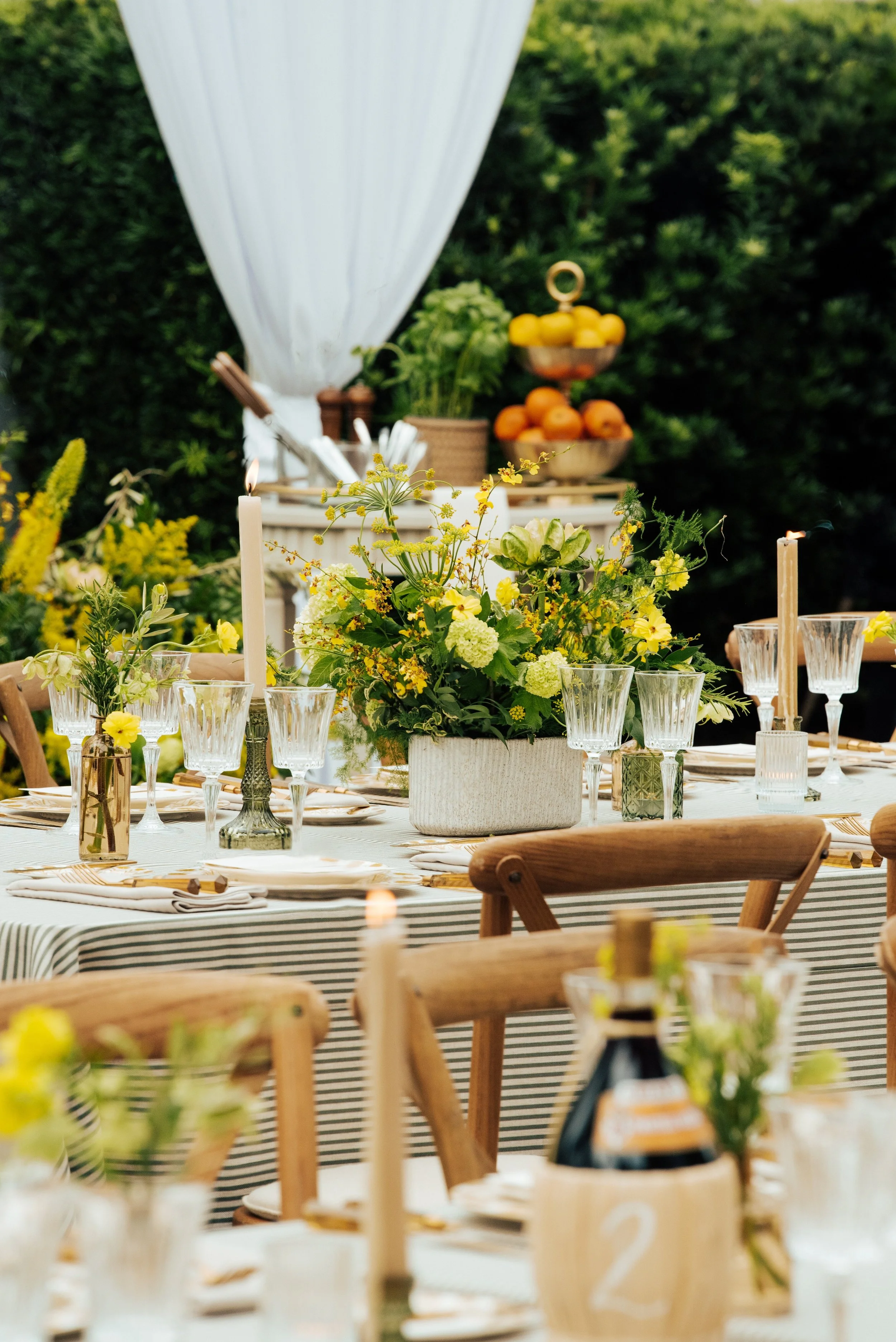 Tablesscape set up with greenery and yellow flowers for an Italian themes wedding rehearsal dinner