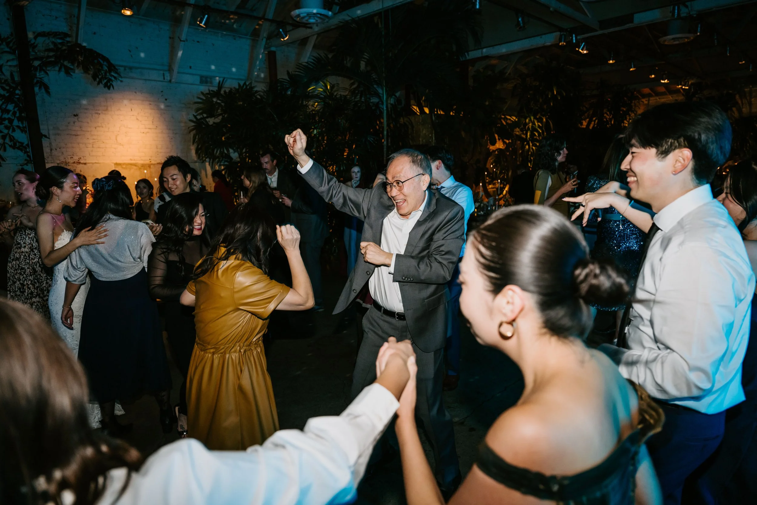 Wedding guest dancing with focus on a man jumping up with his arm in the air