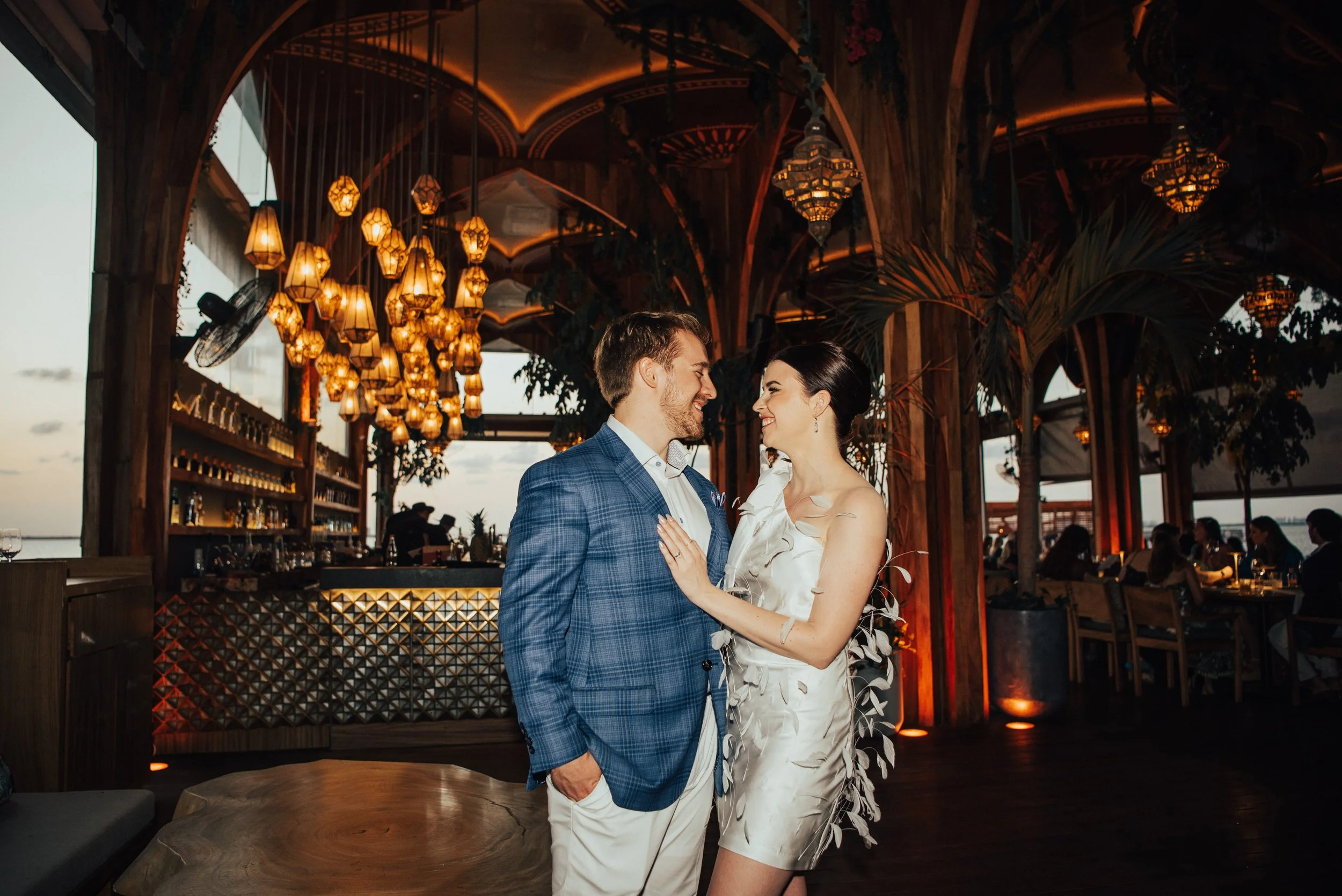 bride and groom smiling at each other with jungle theme restaurant behind them