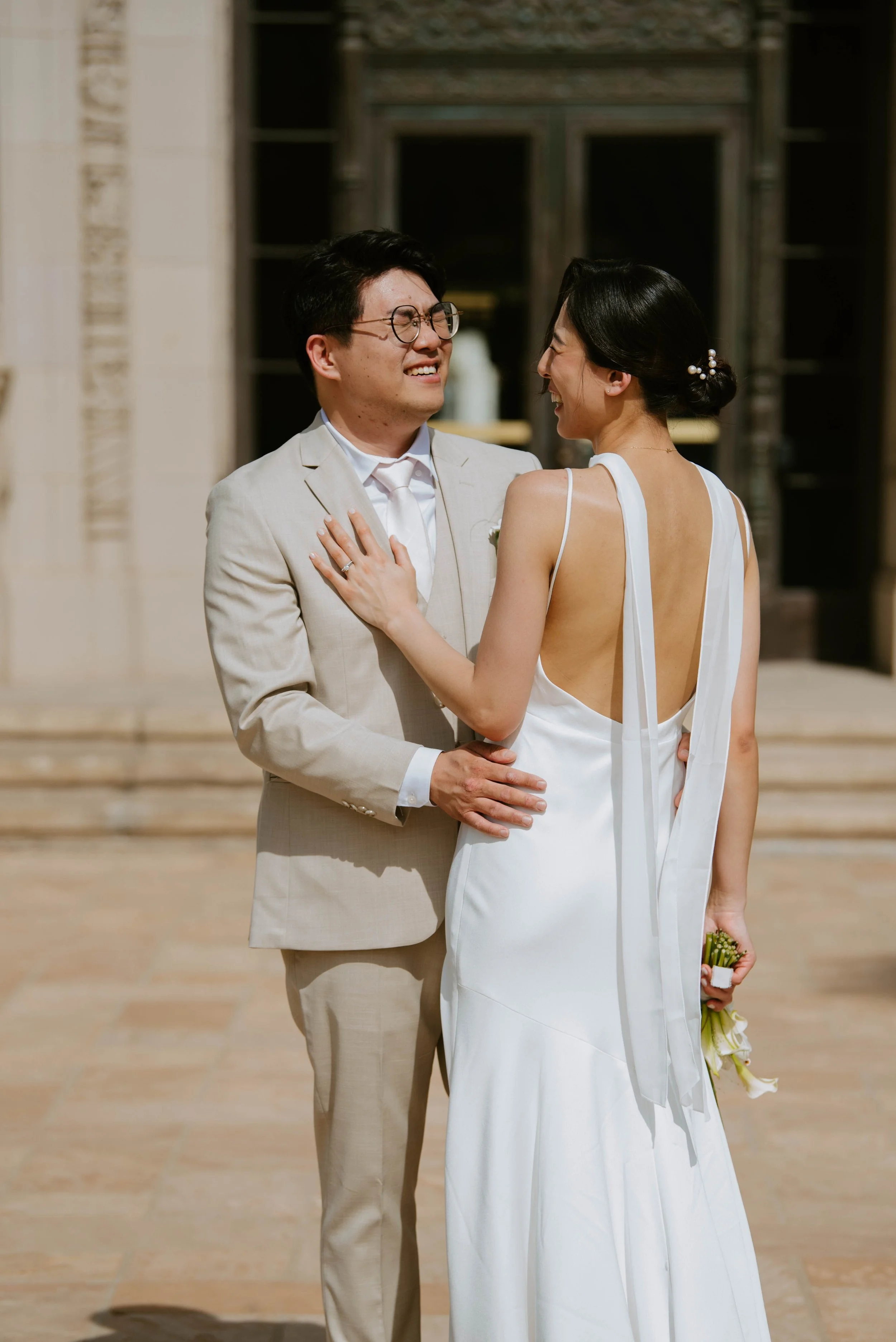 Brides back to the camera with her hand on grooms chest. Groom is facing towards the camera laughing with his eyes closed. His hands are on the brides waist.
