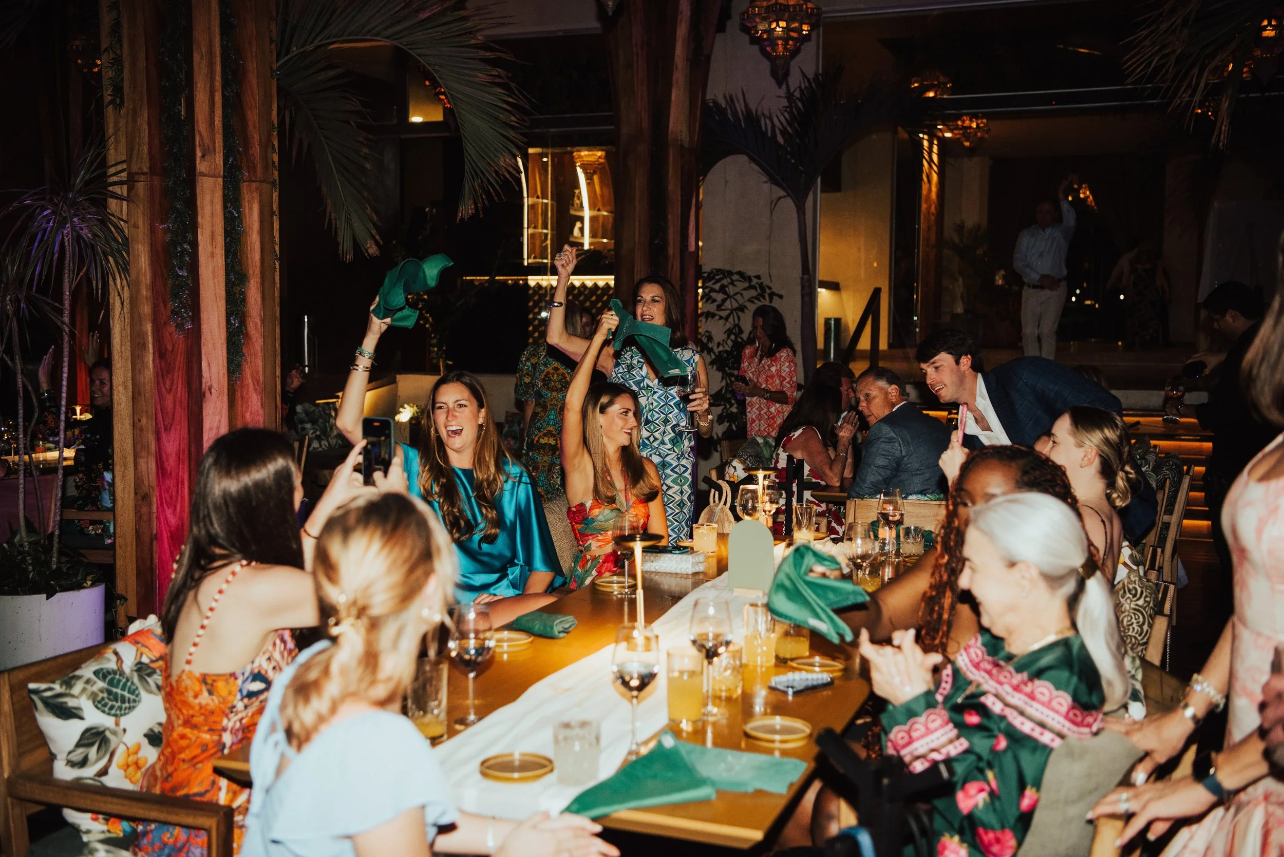 wedding guest cheering at their table. Several guest waving napkins