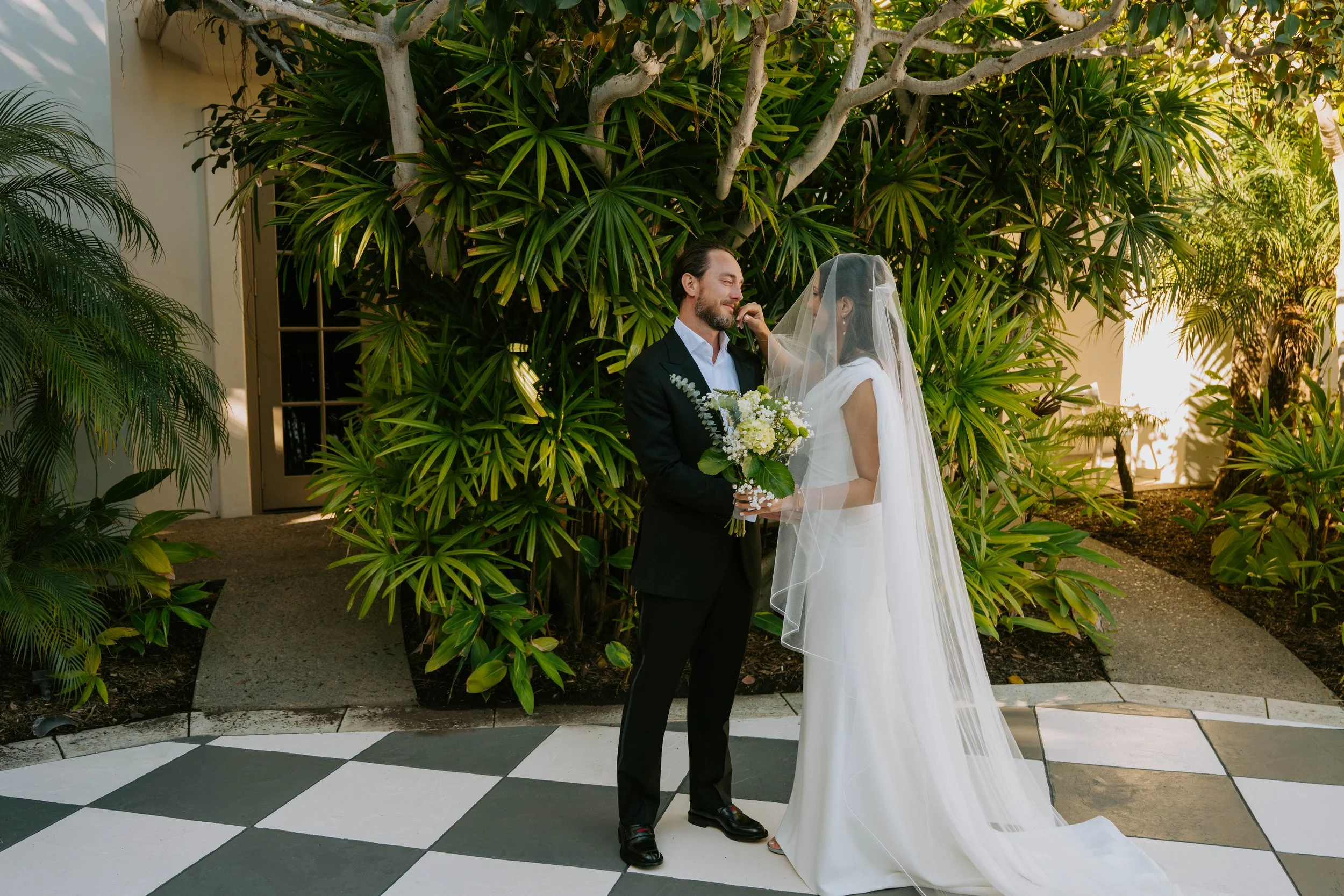 Groom getting emotional as he sees his Bride. Couple is standing in front of a bunch of plants
