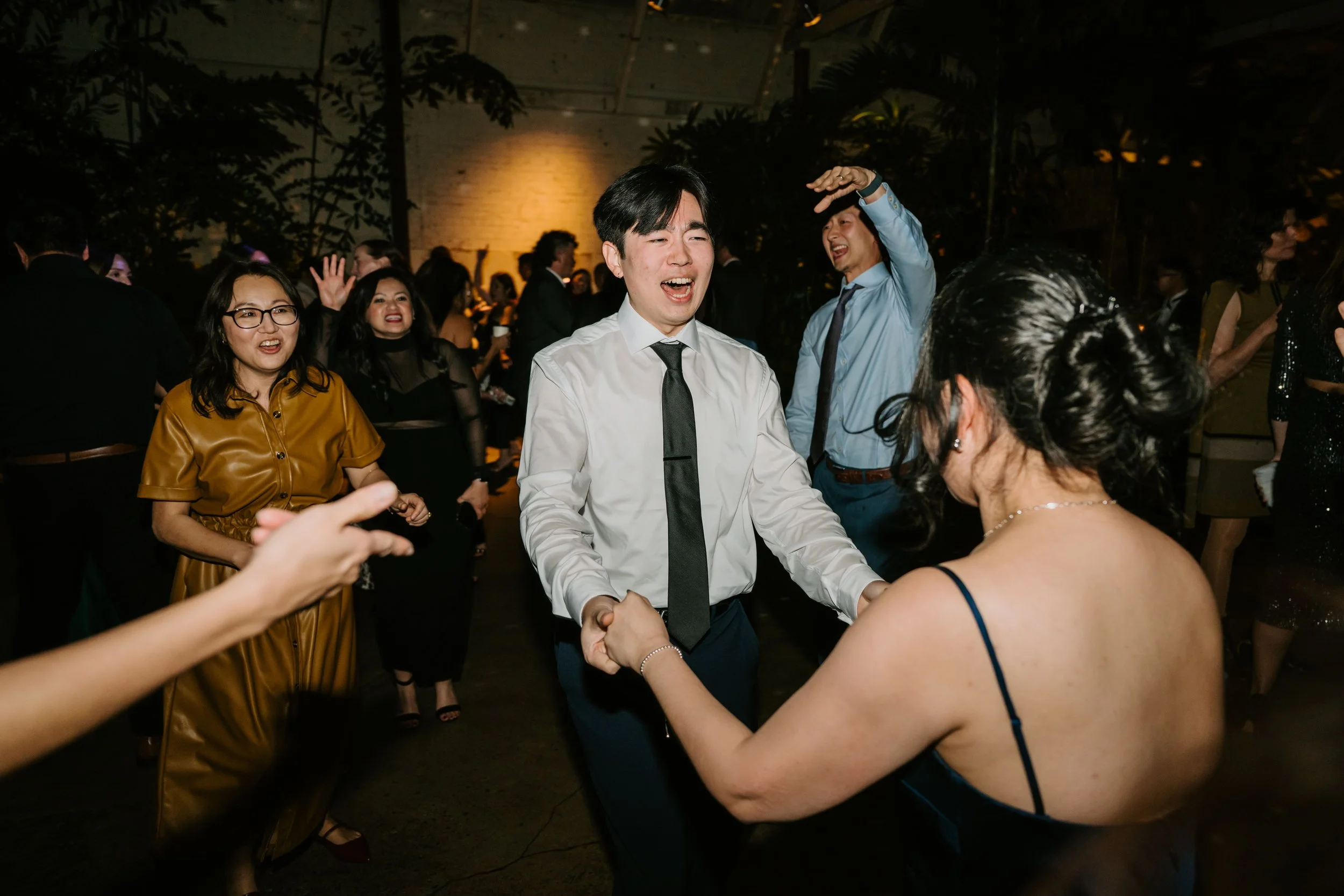 wedding guest singing and holding hands with a woman as they dance