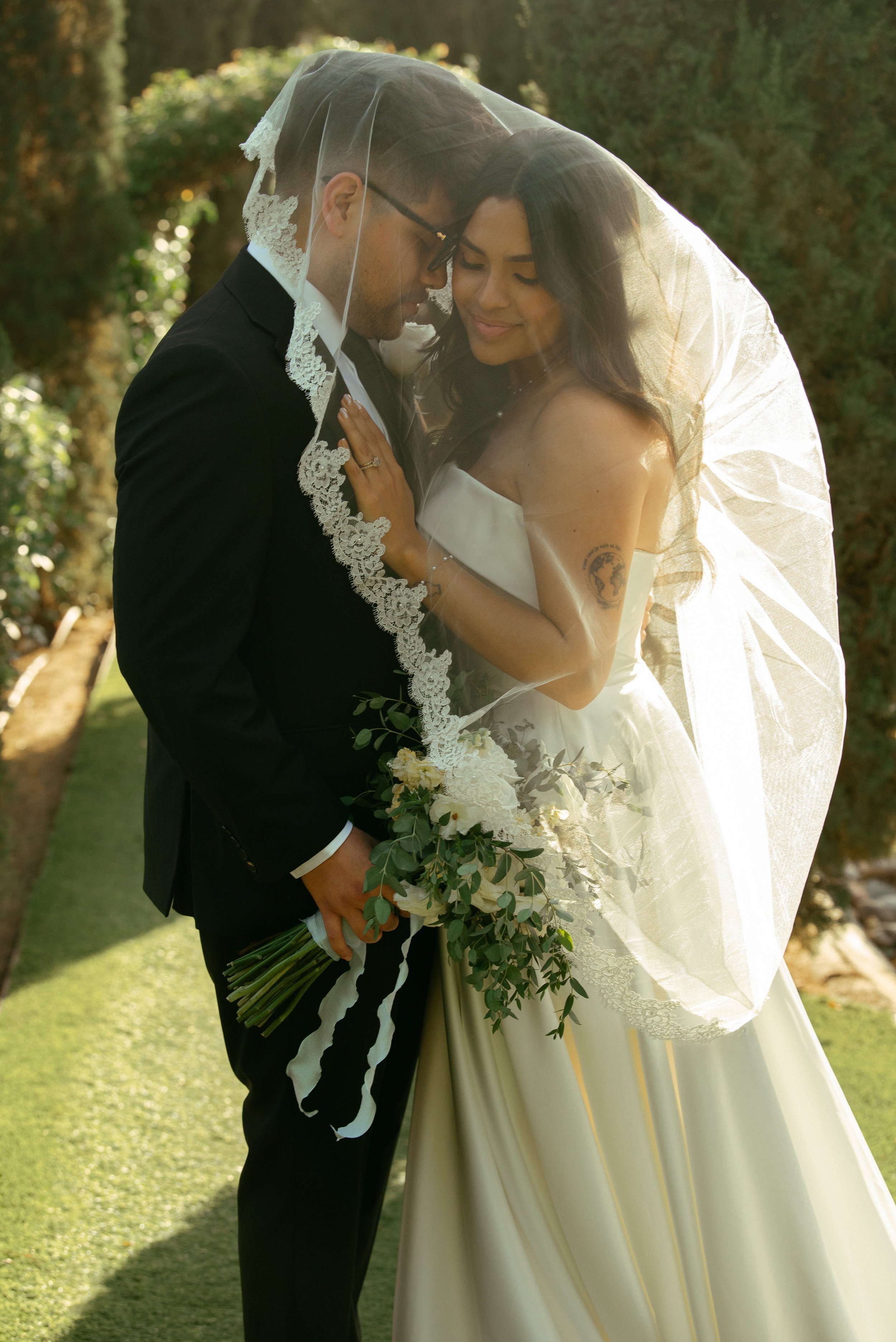 Bride and groom embracing with her veil over them