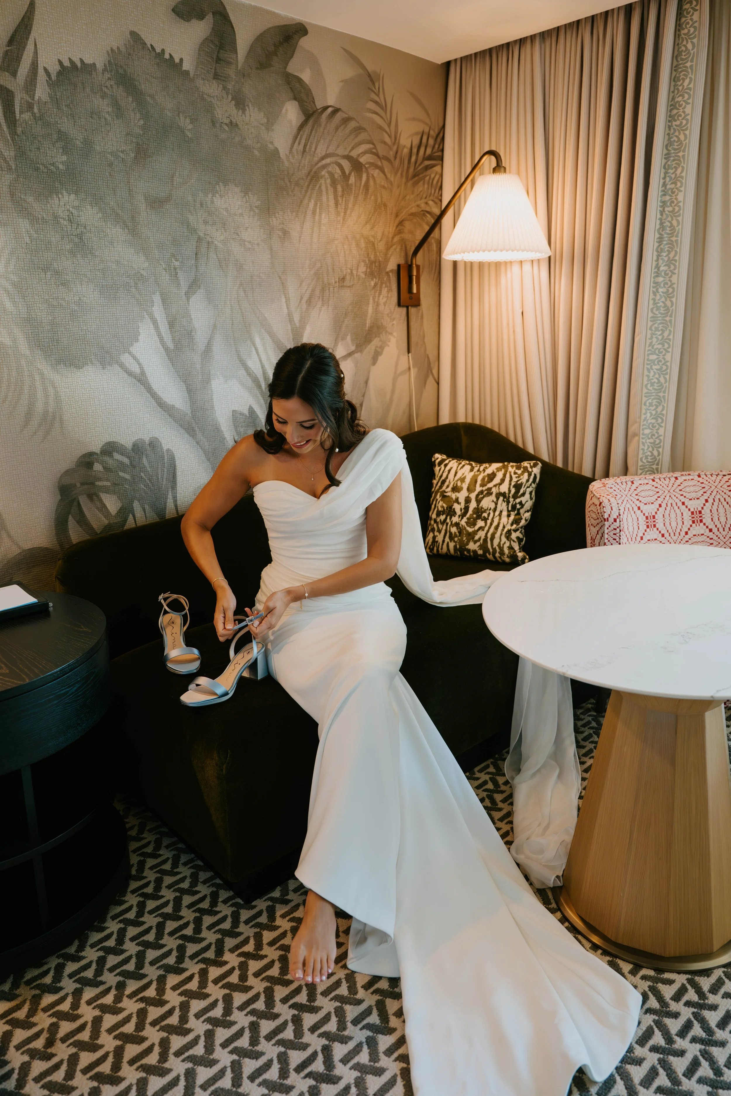 Bride sitting on couch putting on her shoes
