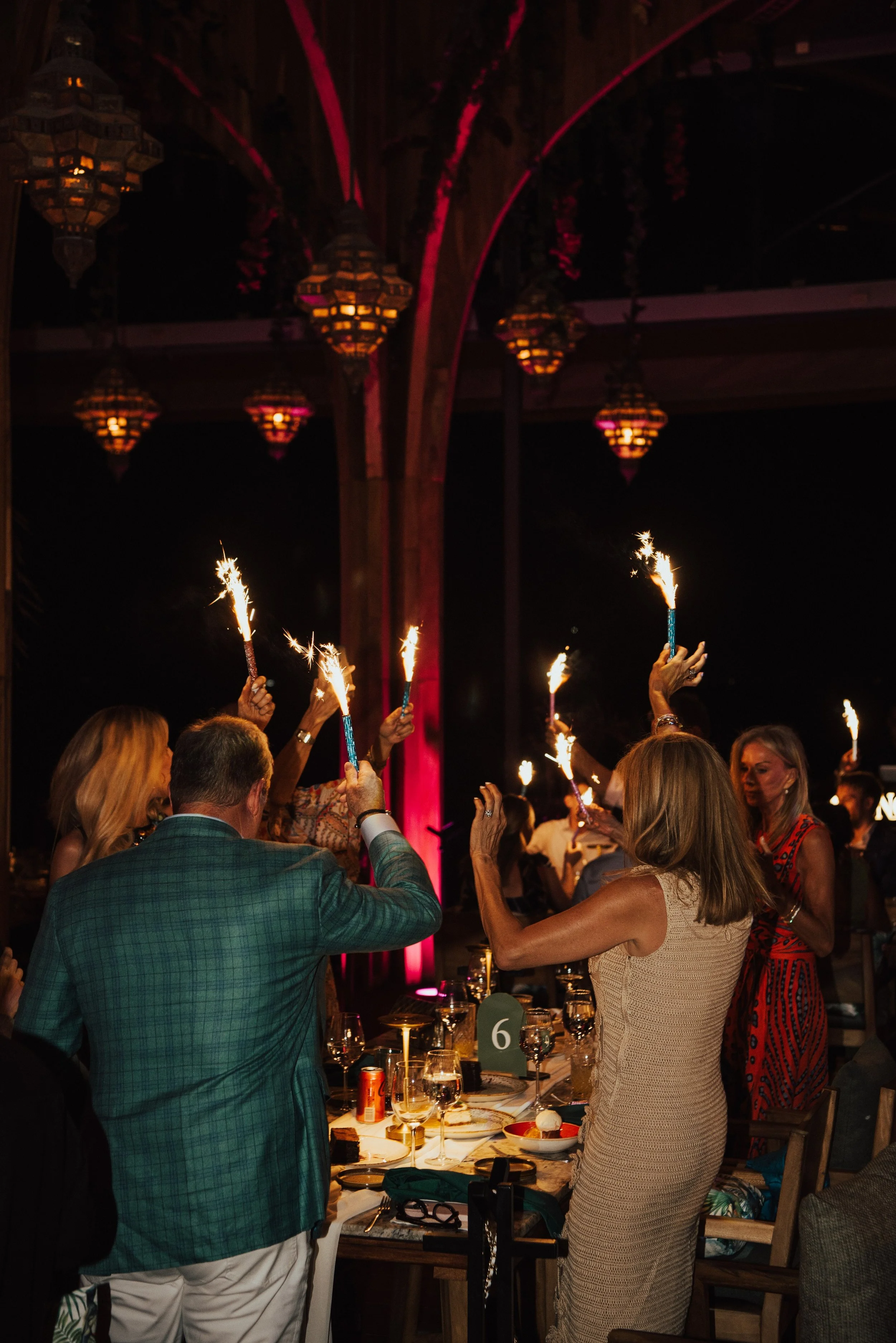 wedding guest dancing at their table with sparklers in hand