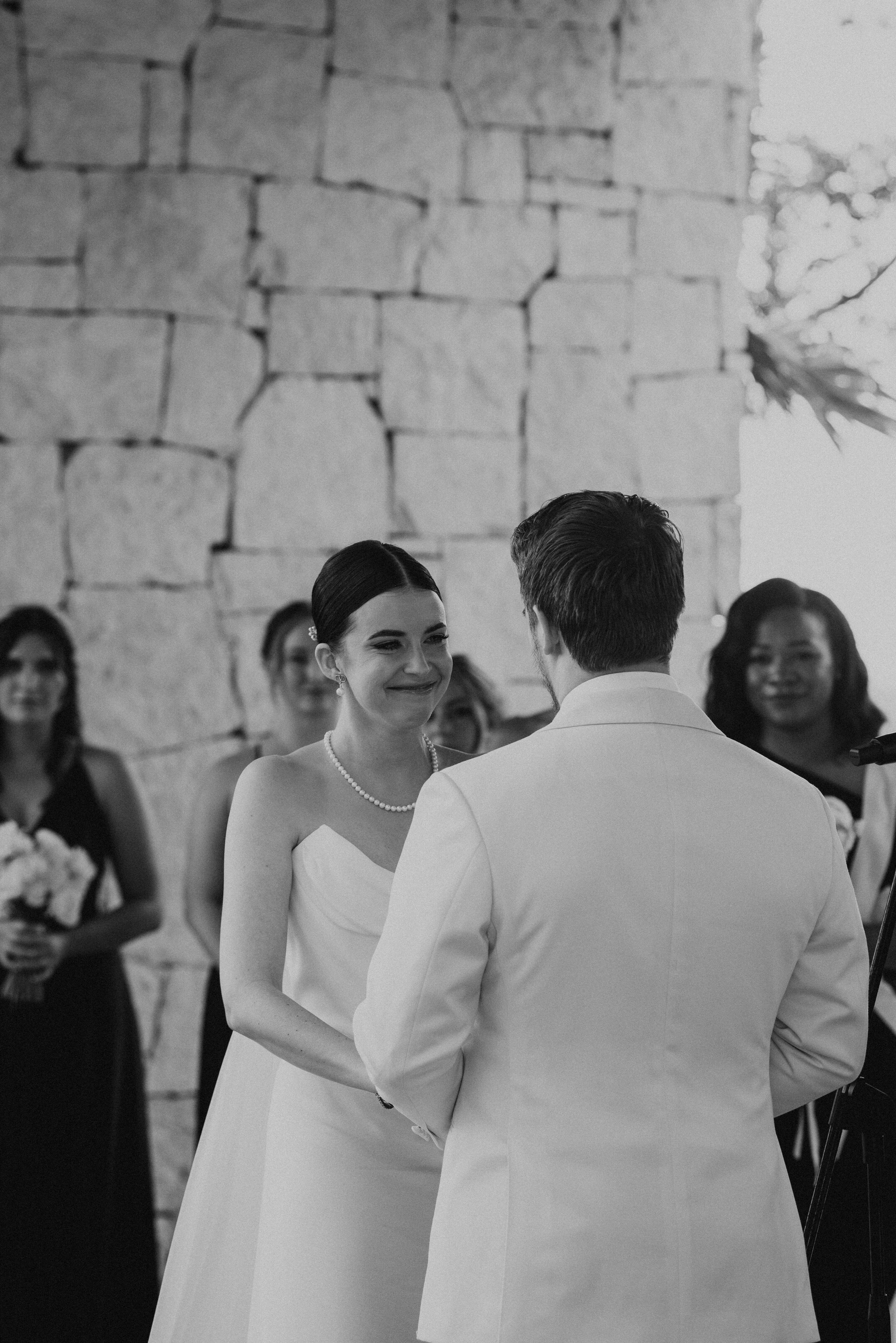 black and white photo of bride smiling at groom. photos is shot over grooms shoulder