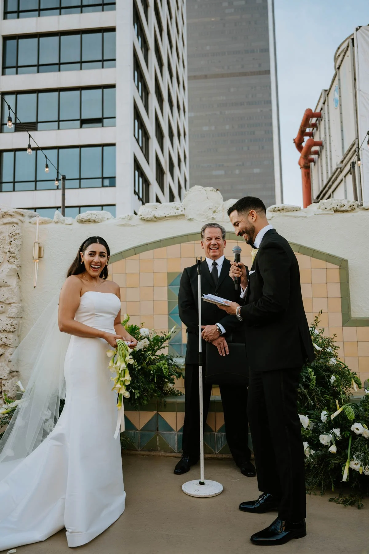 Bride and groom smiling and laughing during their vows.