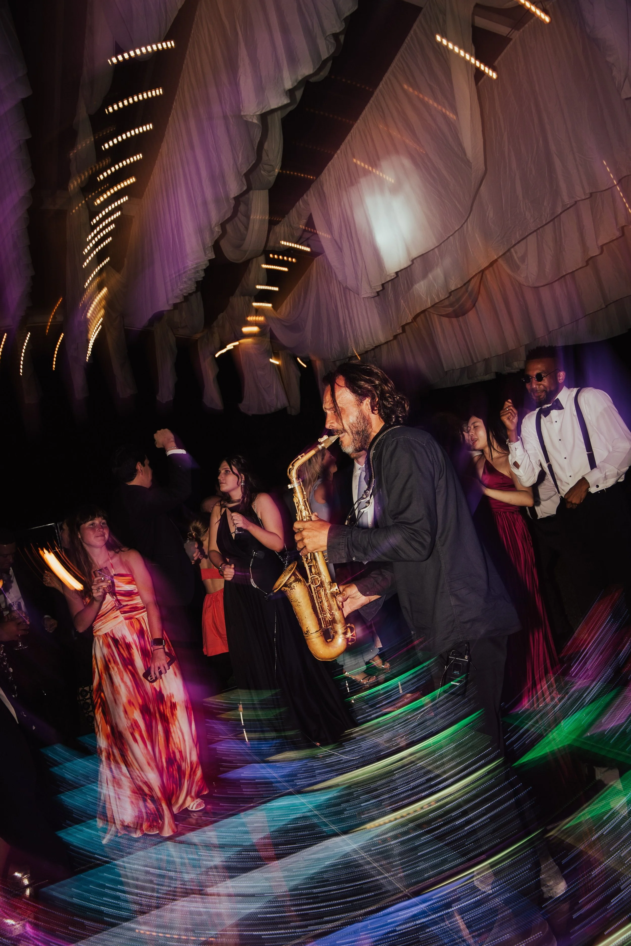man playing a saxophone on the dance floor of a wedding reception