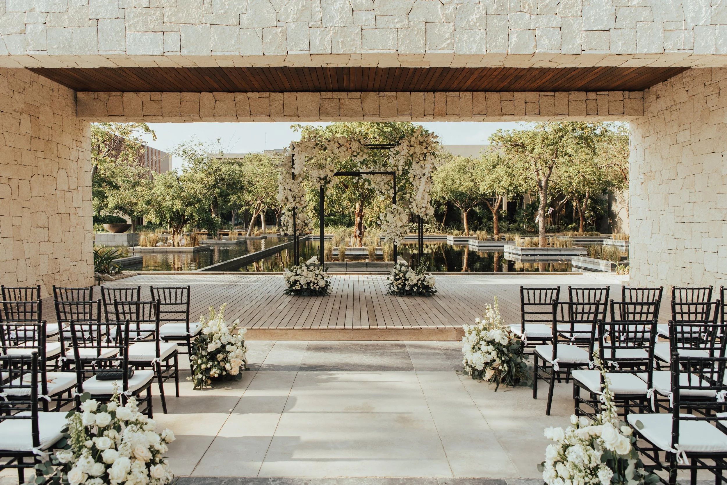 wide shot of wedding ceremony Black space. Rectangle arch covered in white florals.