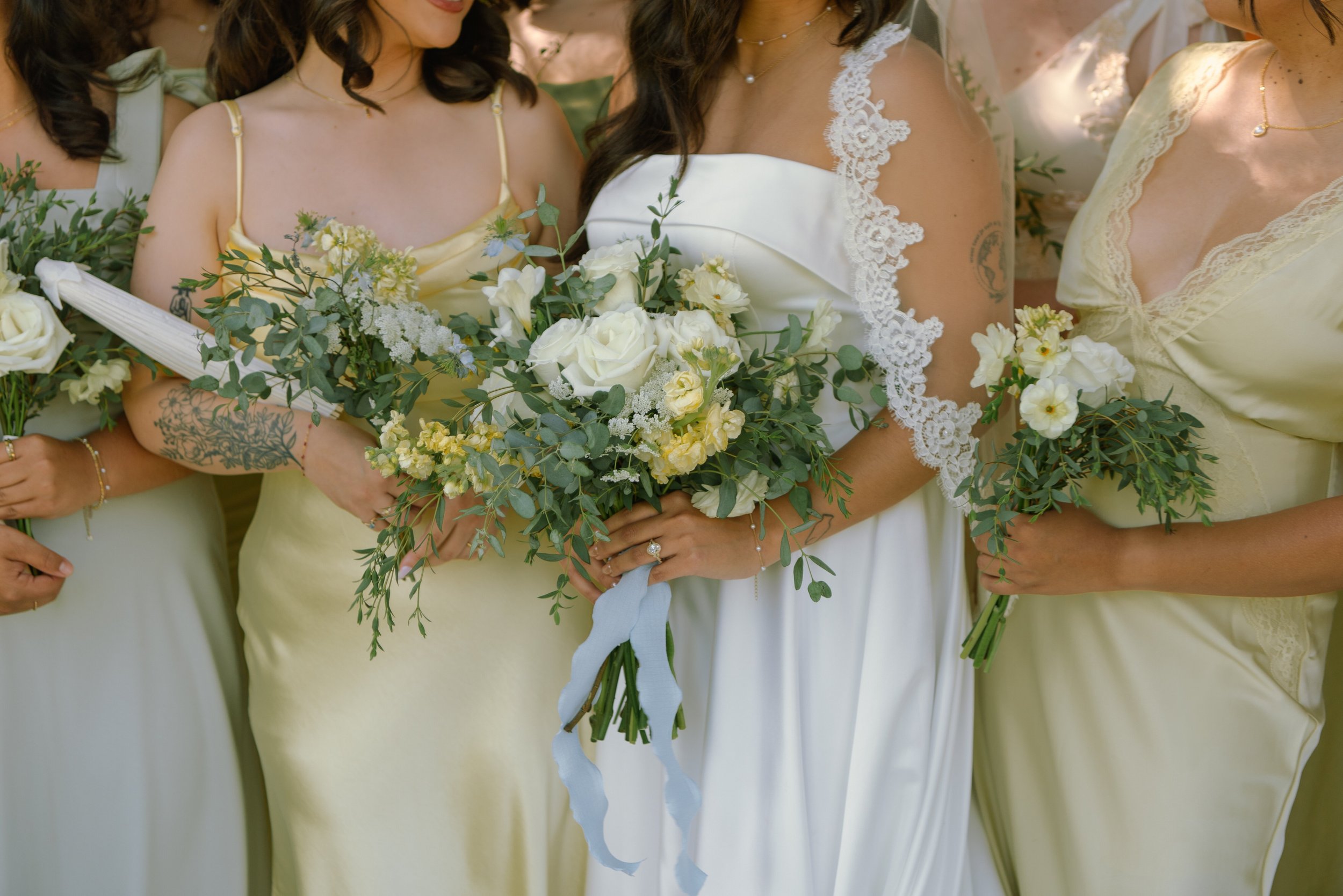 close up shot of bride and bridesmaids holding bouquets. Bridesmaids are wearing yellow and green dresses