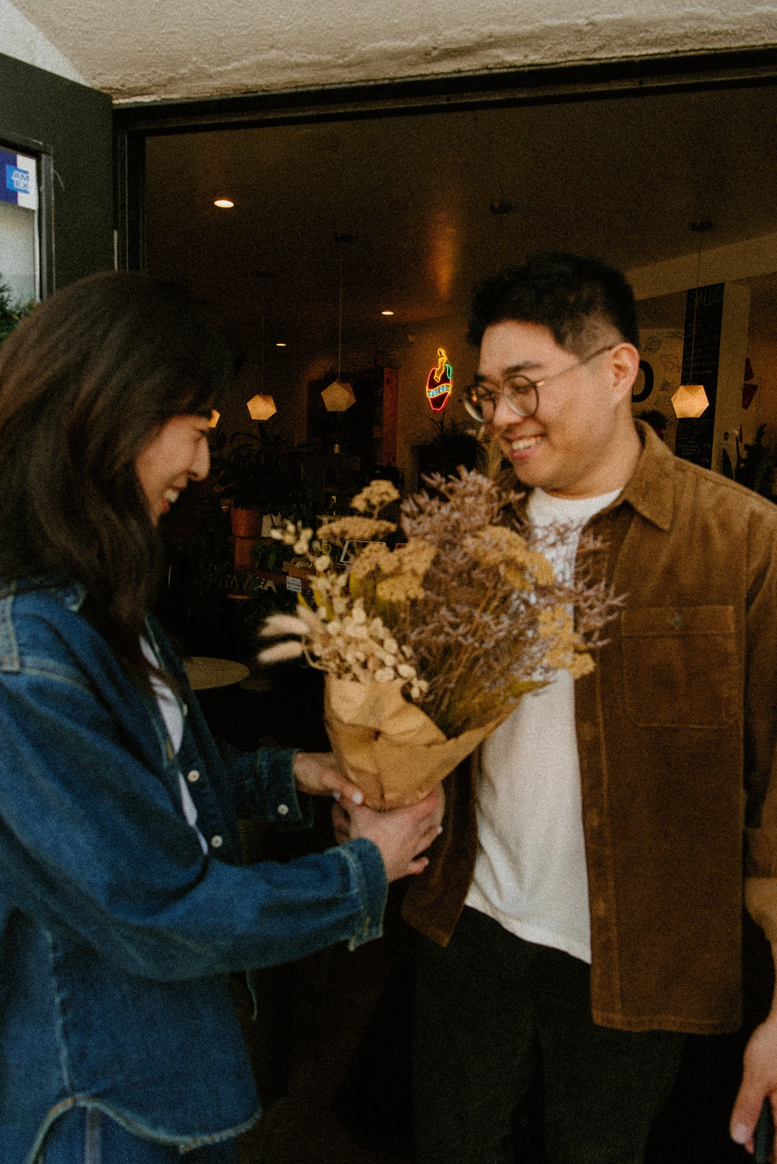 grainy photo of guy giving girl flowers in front of a store