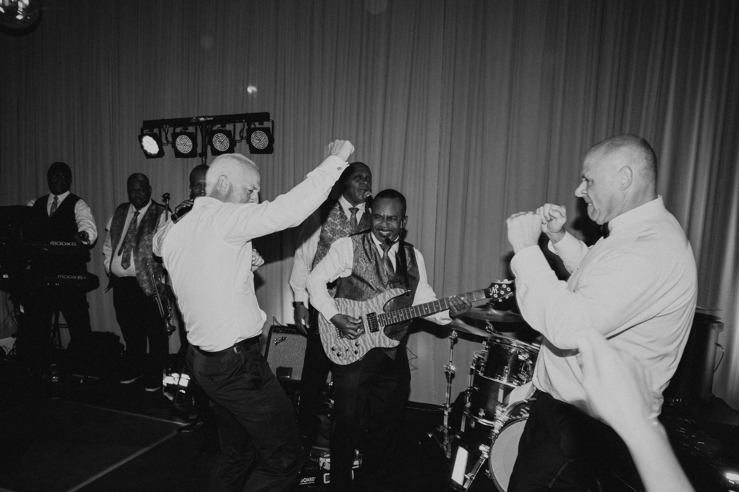 fathers of the bride and groom dancing on stage with the live band
