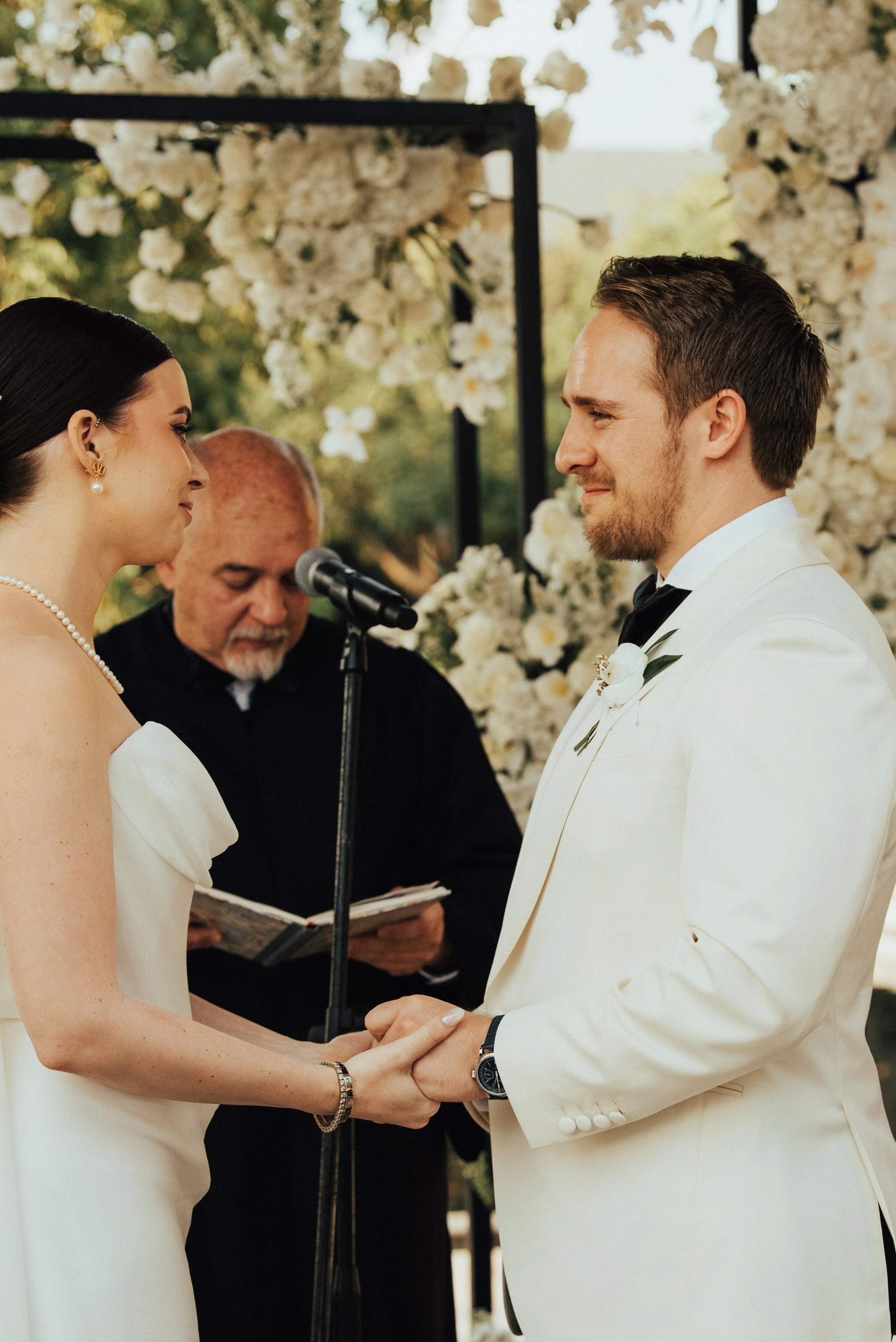 close up of a groom in with suit jacket looking and smile at his bride during their wedding ceremony