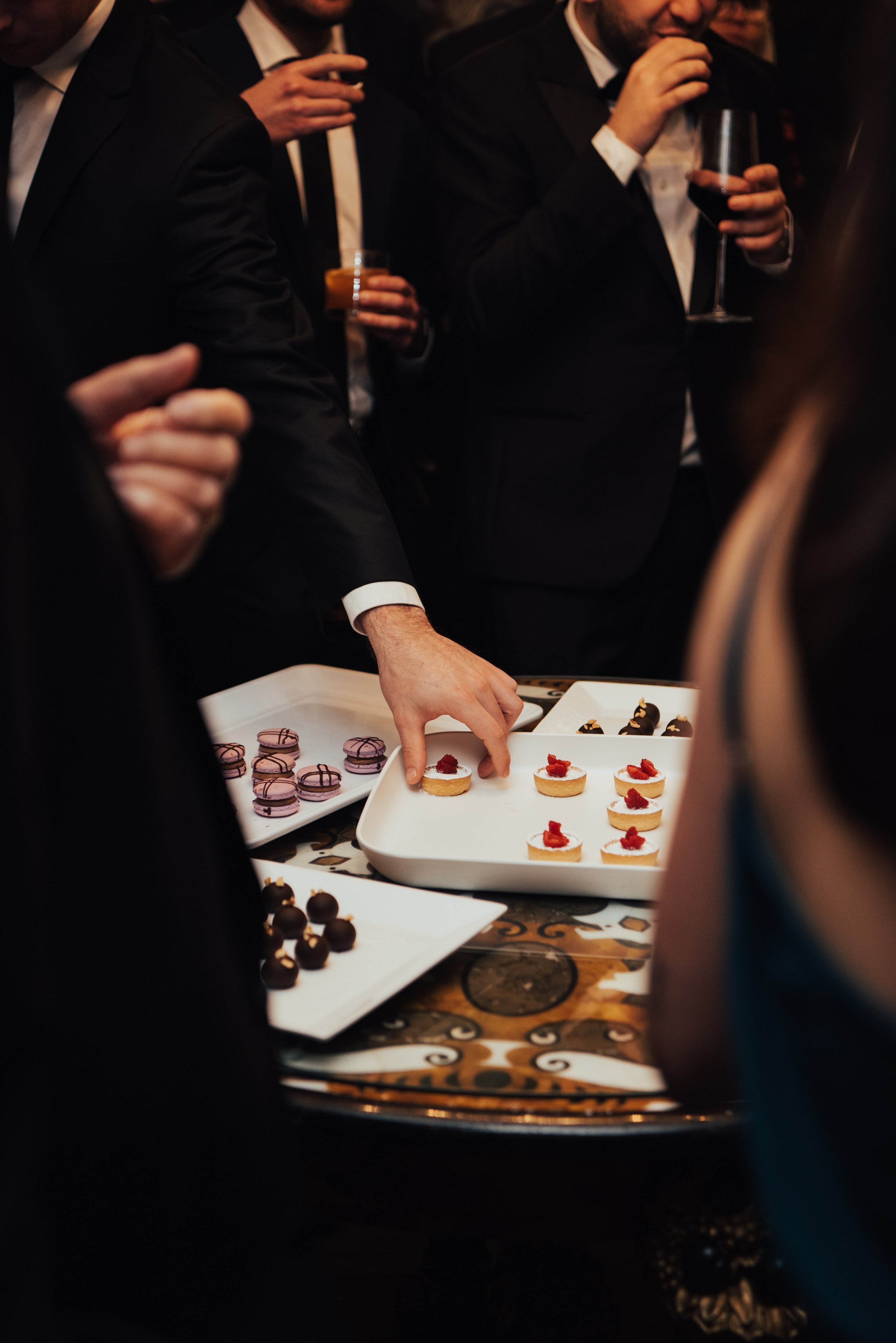 close up photo of wedding guest grabbing a dessert of a white tray.