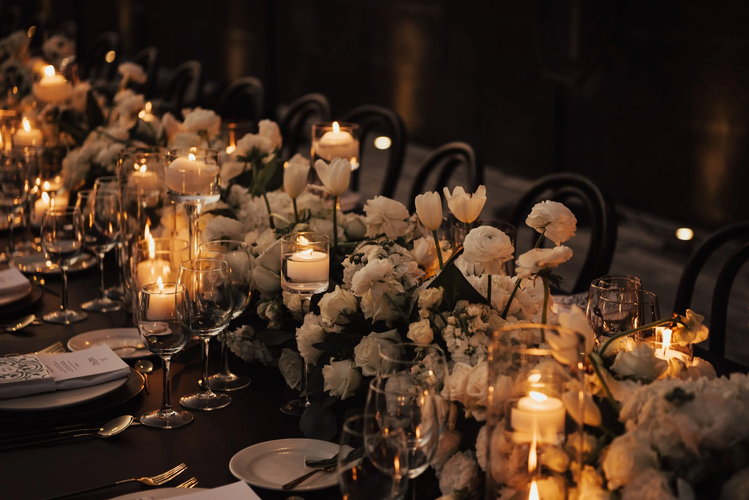 Wedding reception tables set up with white florals and candles along the middle