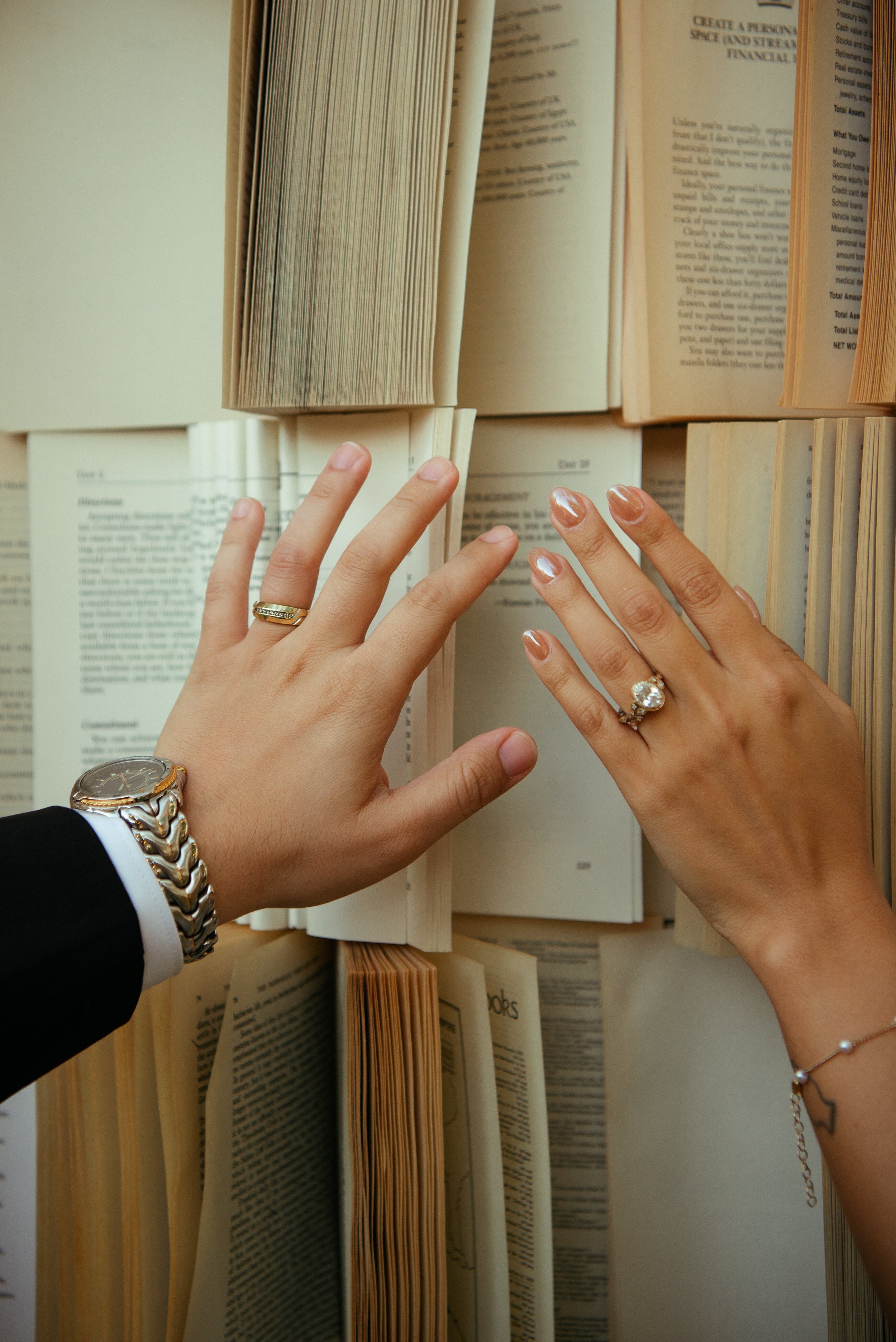Close up of Bride and grooms hands with their rings in front of open books