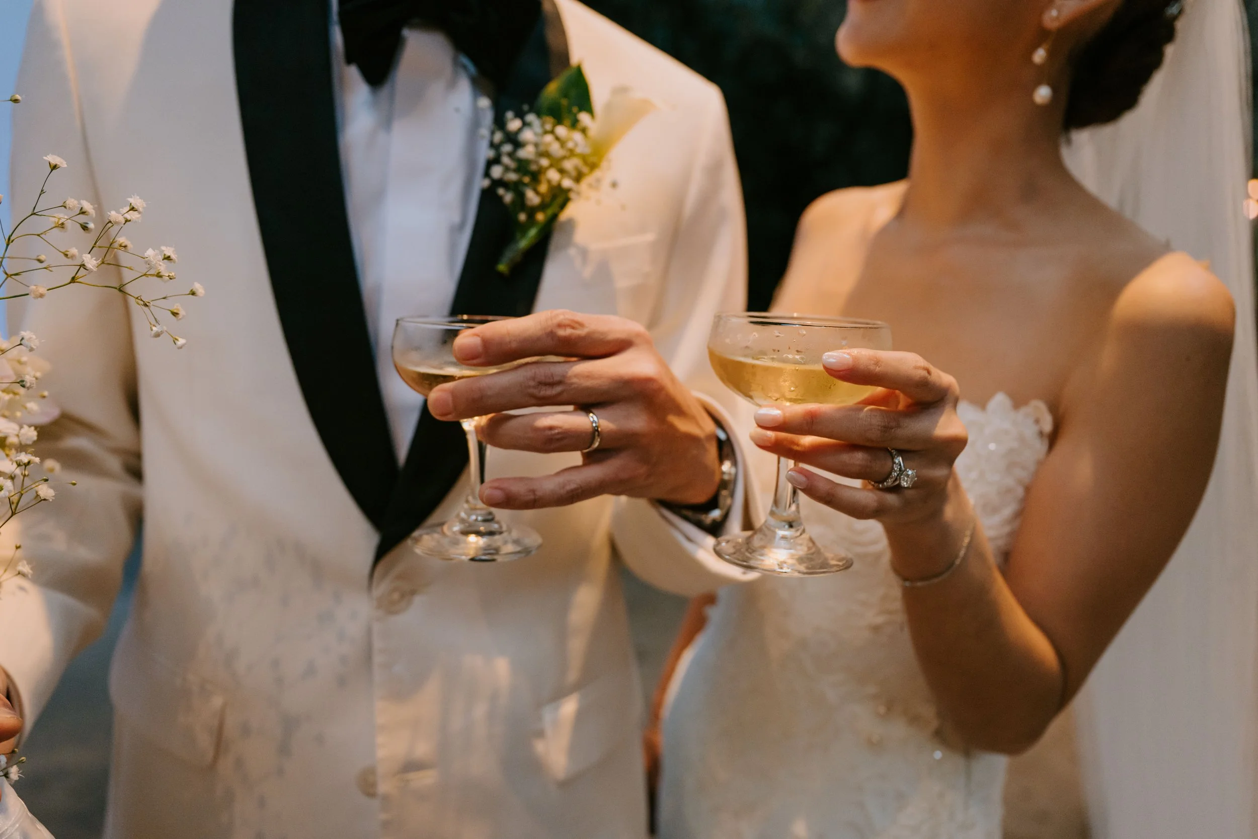 close up shot of bride and groom holding glasses with their wedding rings showing