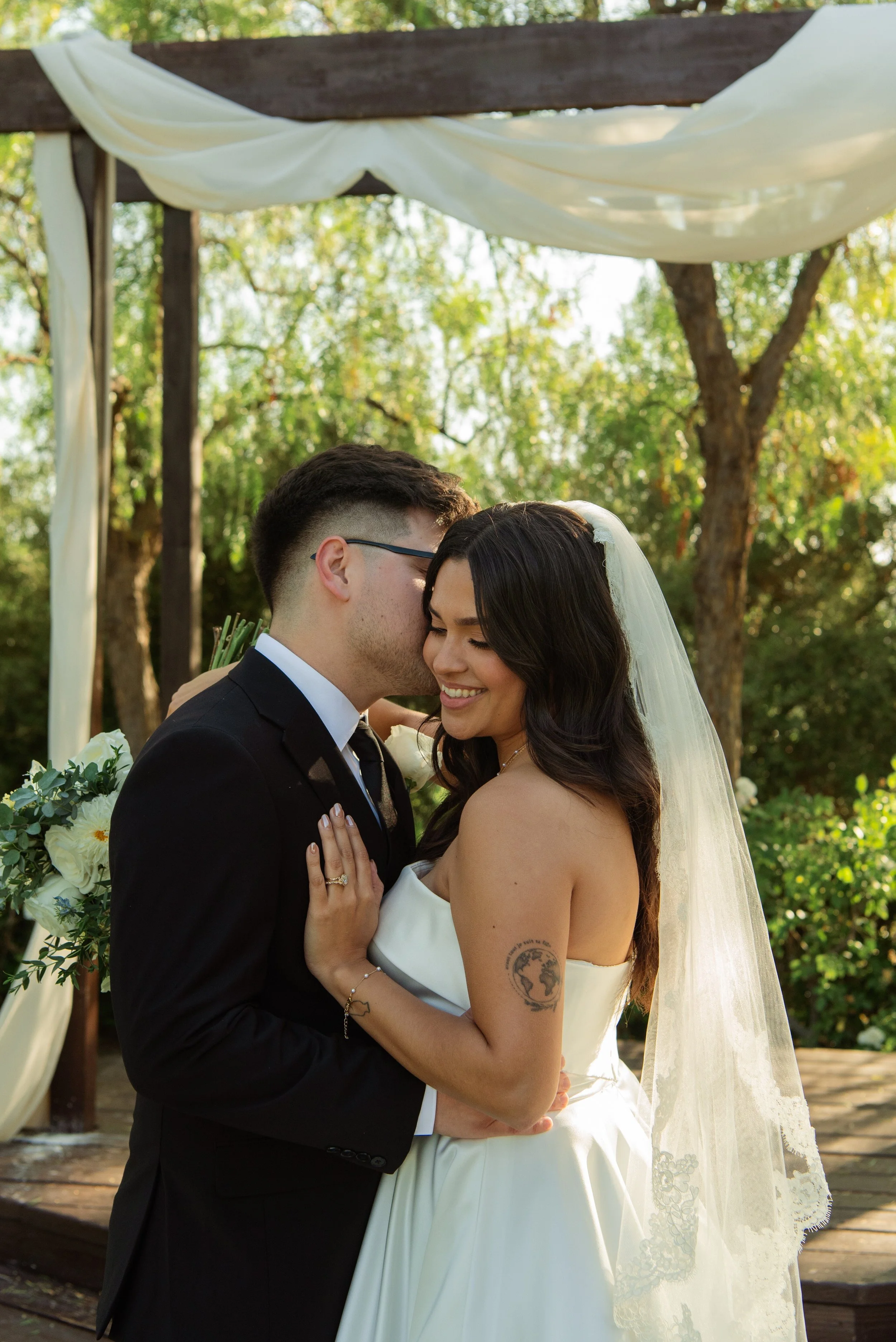 Shot of Groom kissing his bride cheek as she smiles