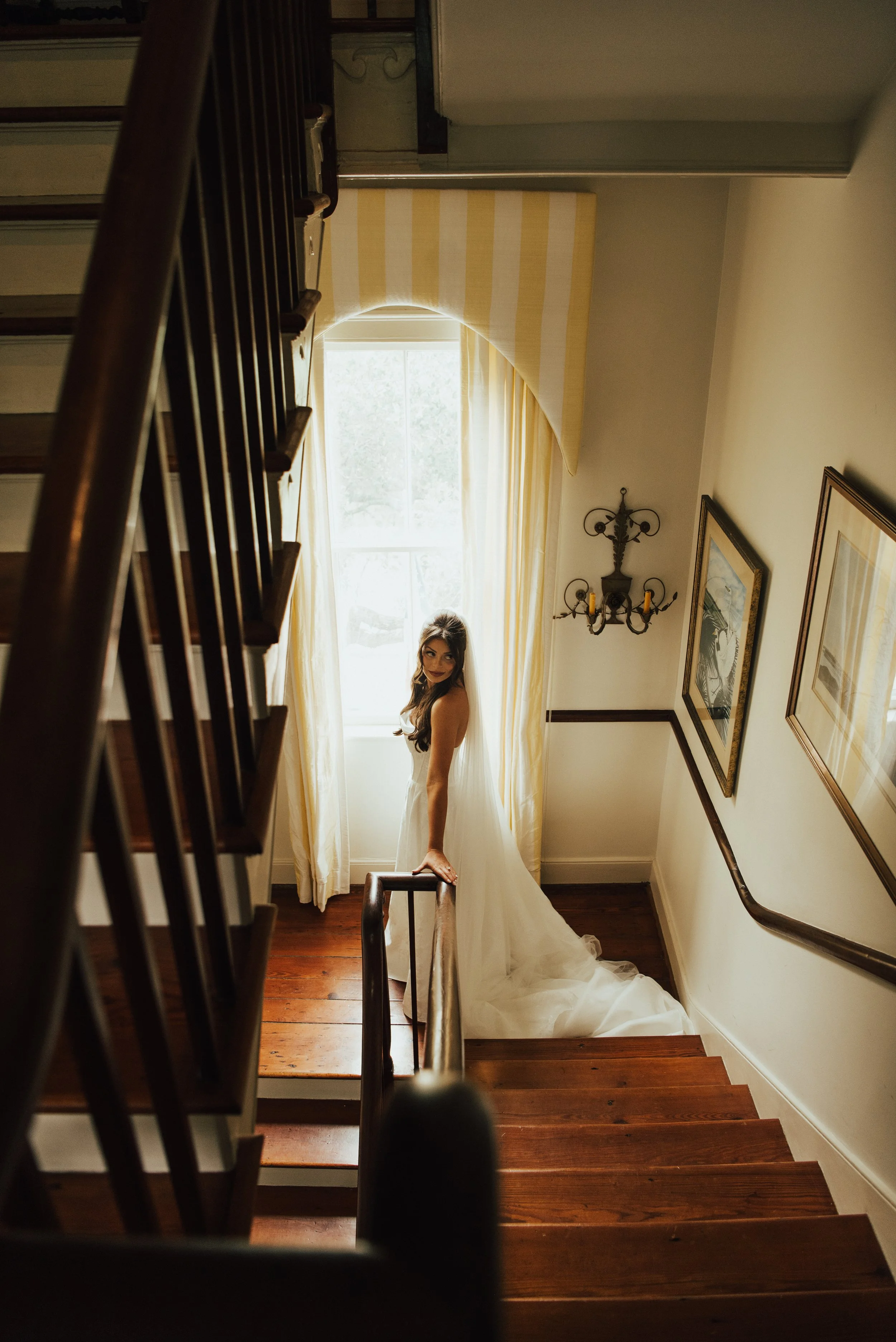 Bride standing at the bottom of the stairs looking over her shoulder