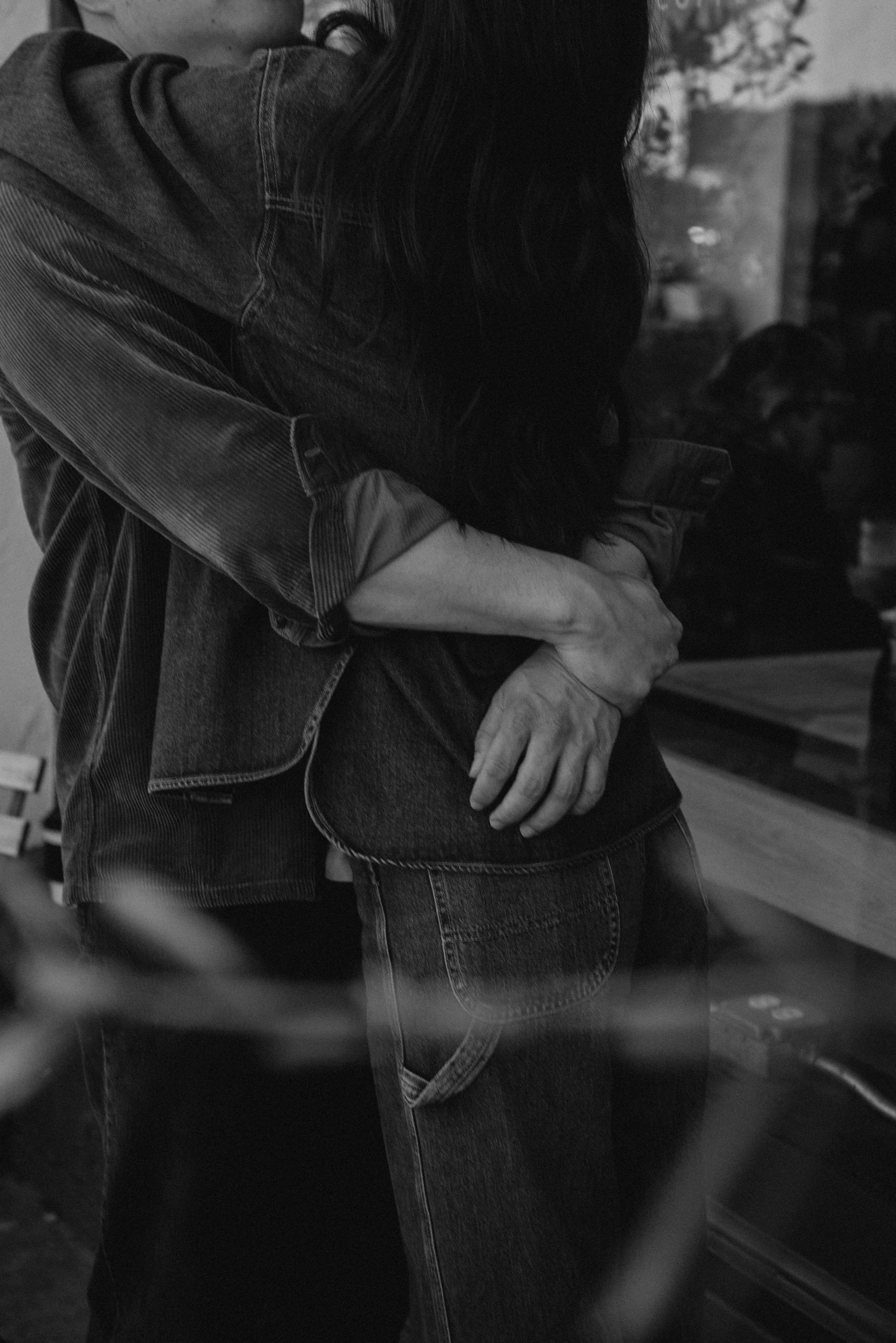 close up black and white photo of guys hands around girls back as they hug