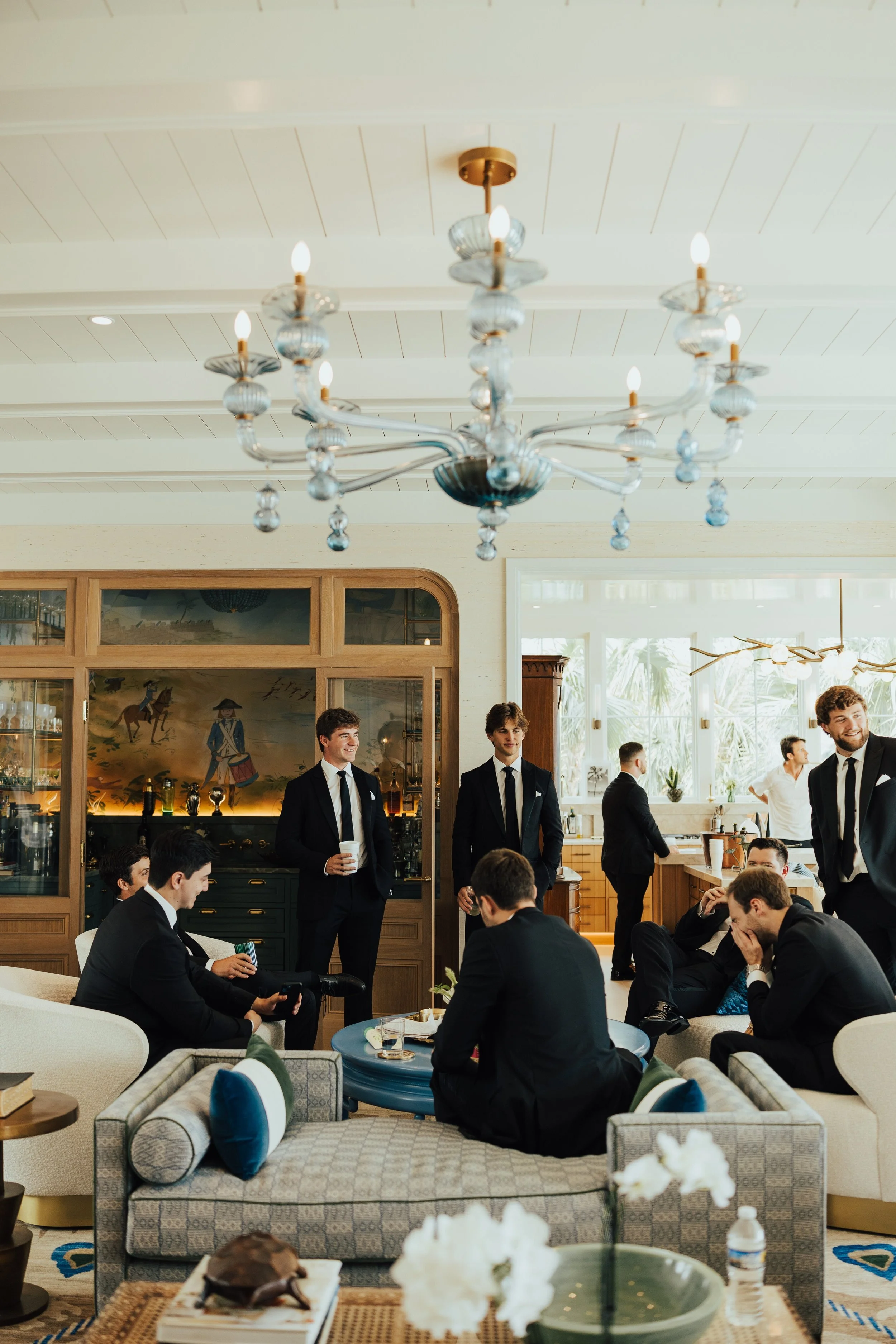 Groomsmen standing and sitting around a living room enjoying a drink