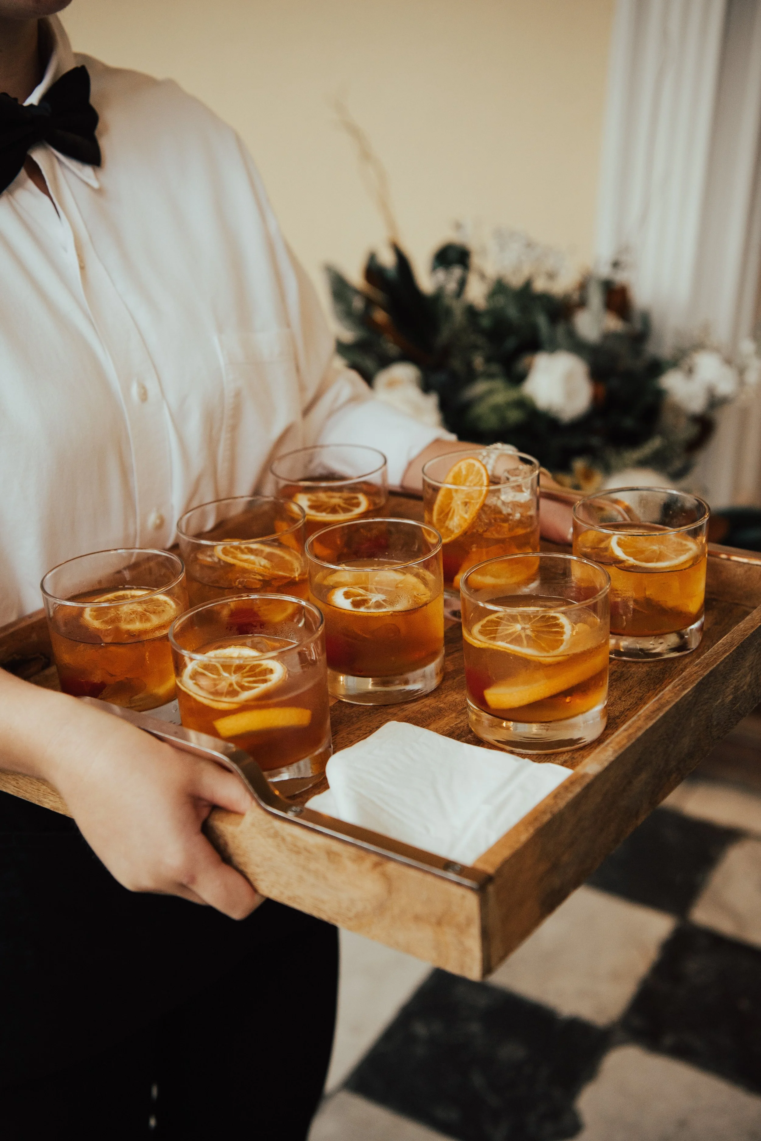 Close up shot of server holding a wooded tray of cocktails