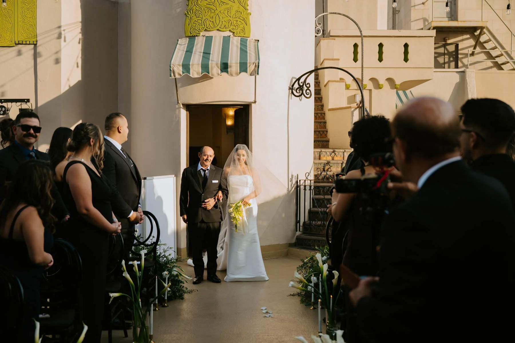 Bride and her father walking down the aisle with guest looking on