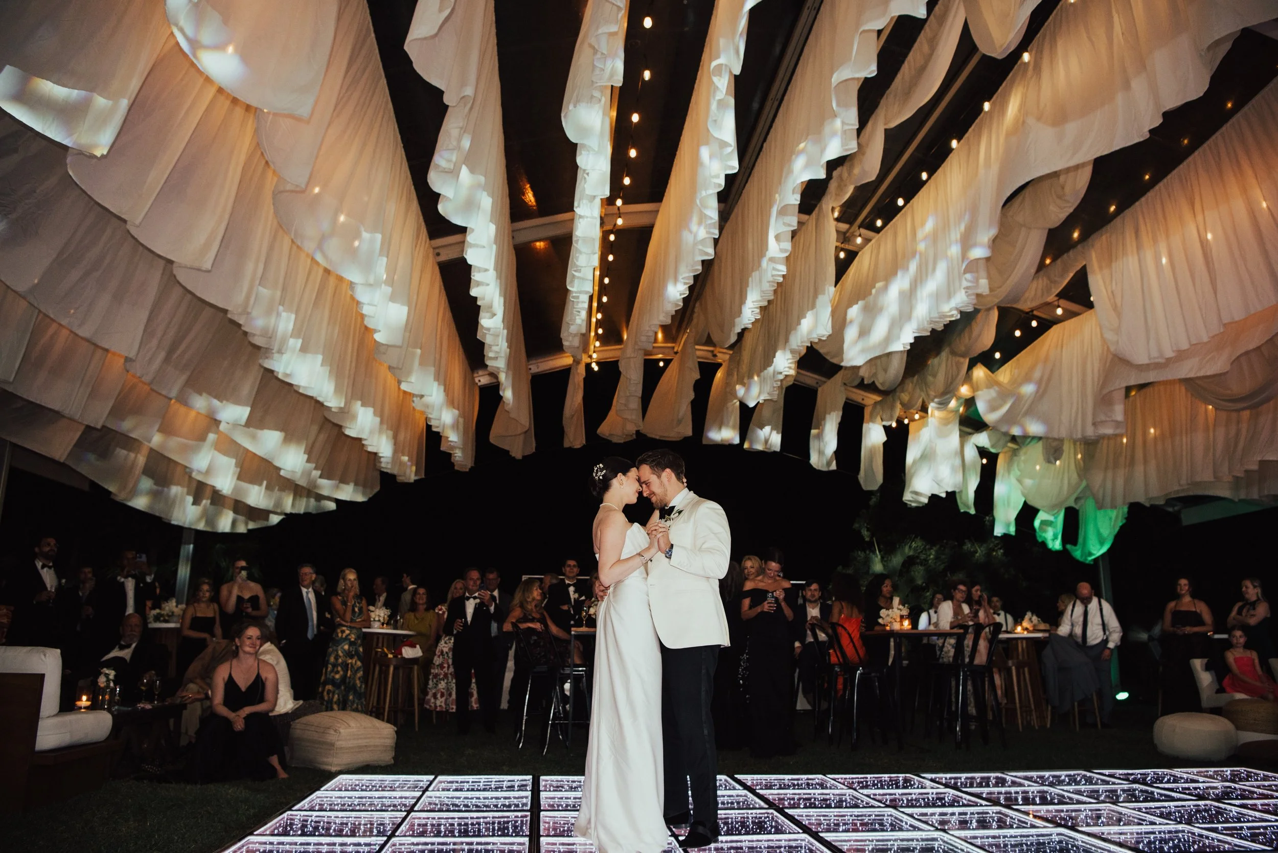 bride and groom dancing with their foreheads together under a tent with white fabric hanging from the ceiling