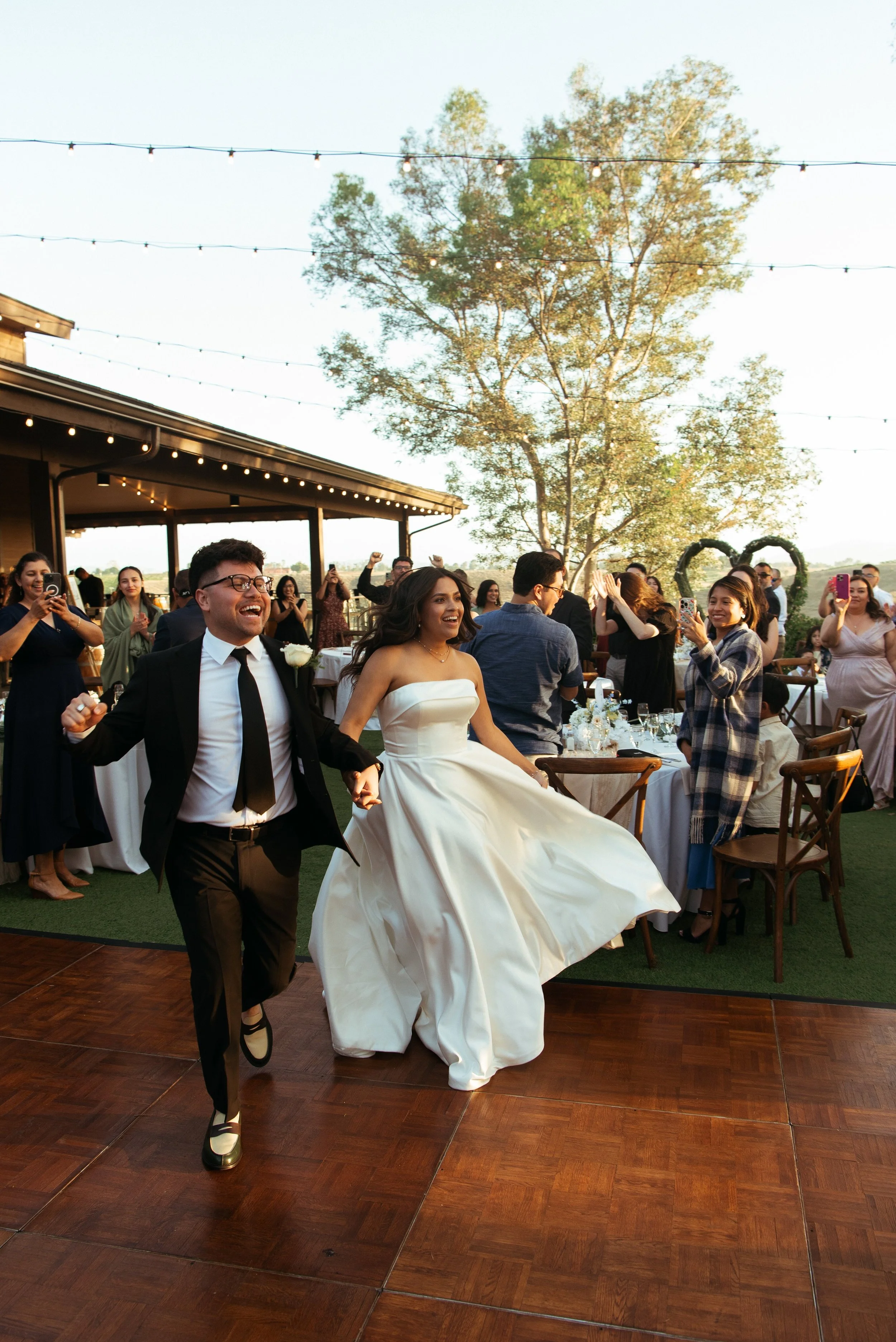 Bride and groom running into their receptions with smiles on their faces as guest cheer
