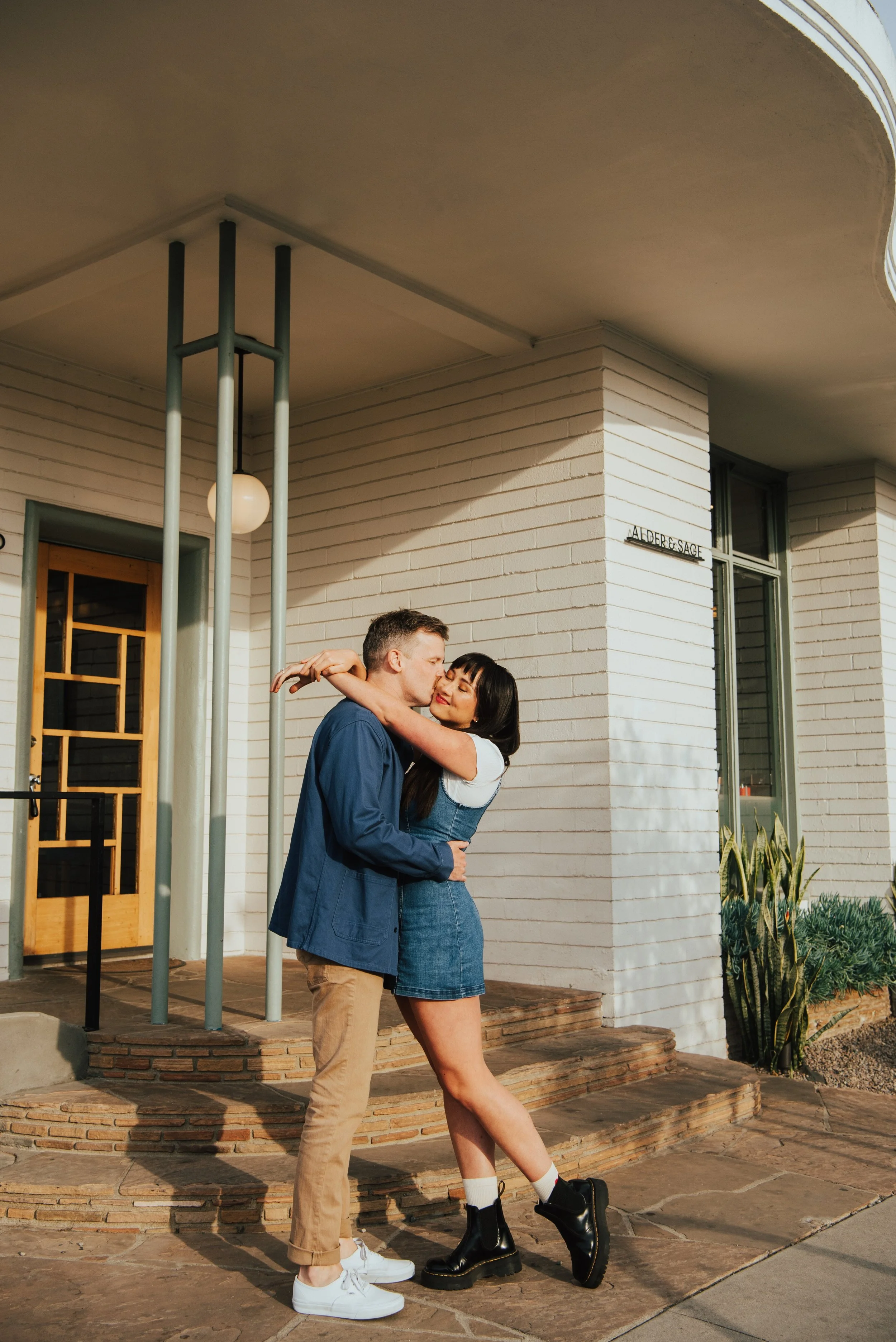 photo of girl falling into guy with her arms around his neck and he is kissing her cheek.