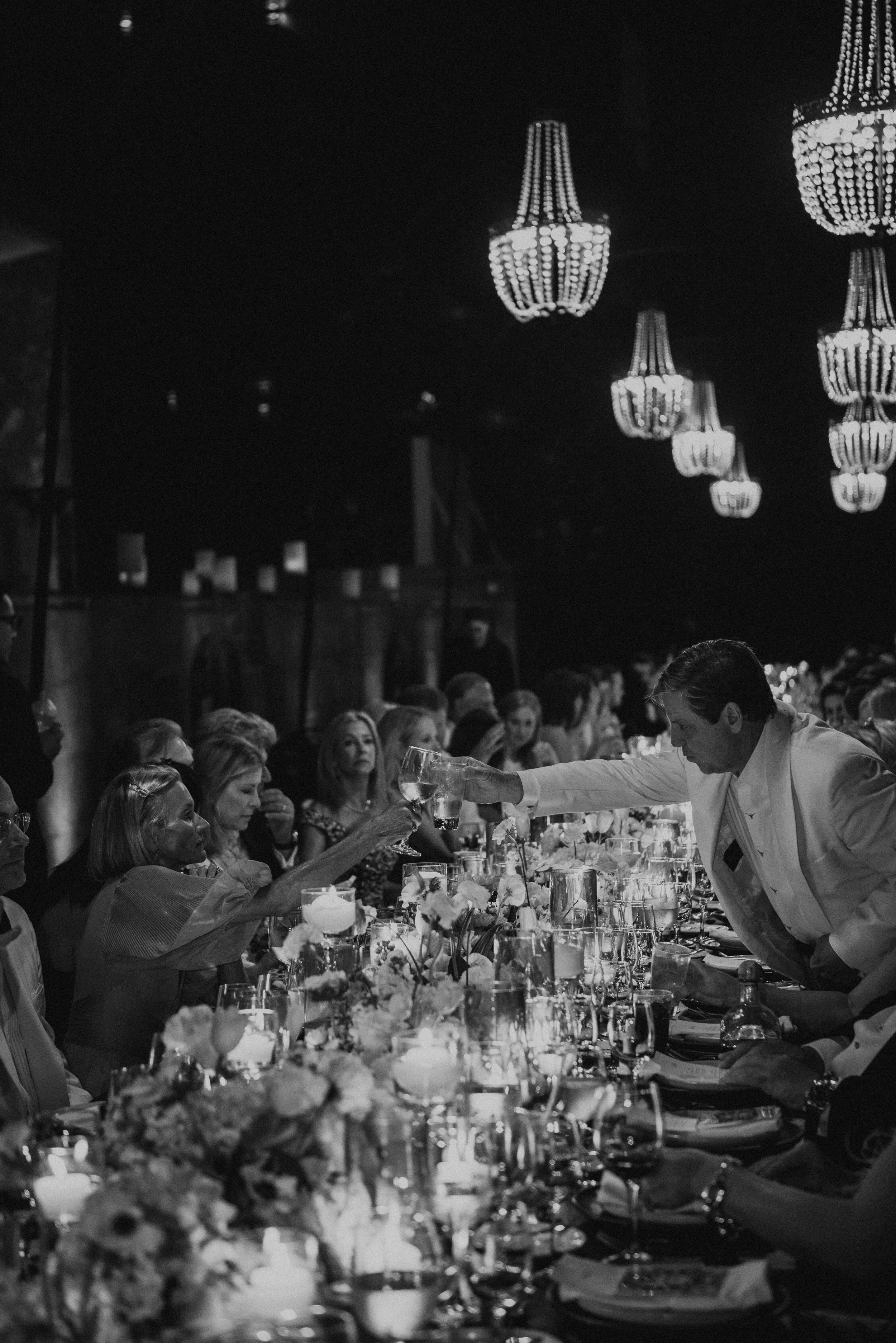 black and white photo of wedding guest cheersing over table