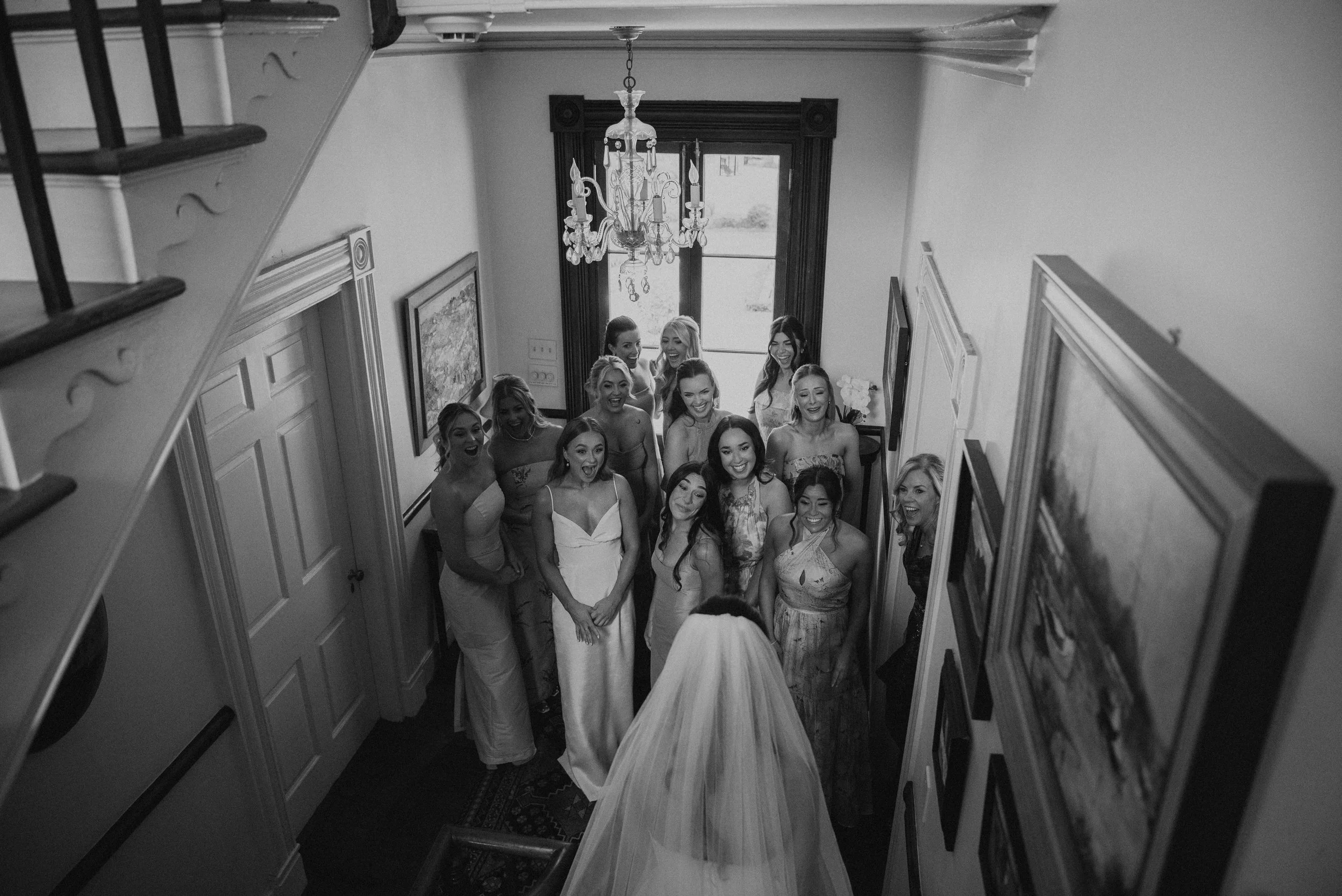 black and white photo of bridesmaid seeing the bride in her dress for the first ime