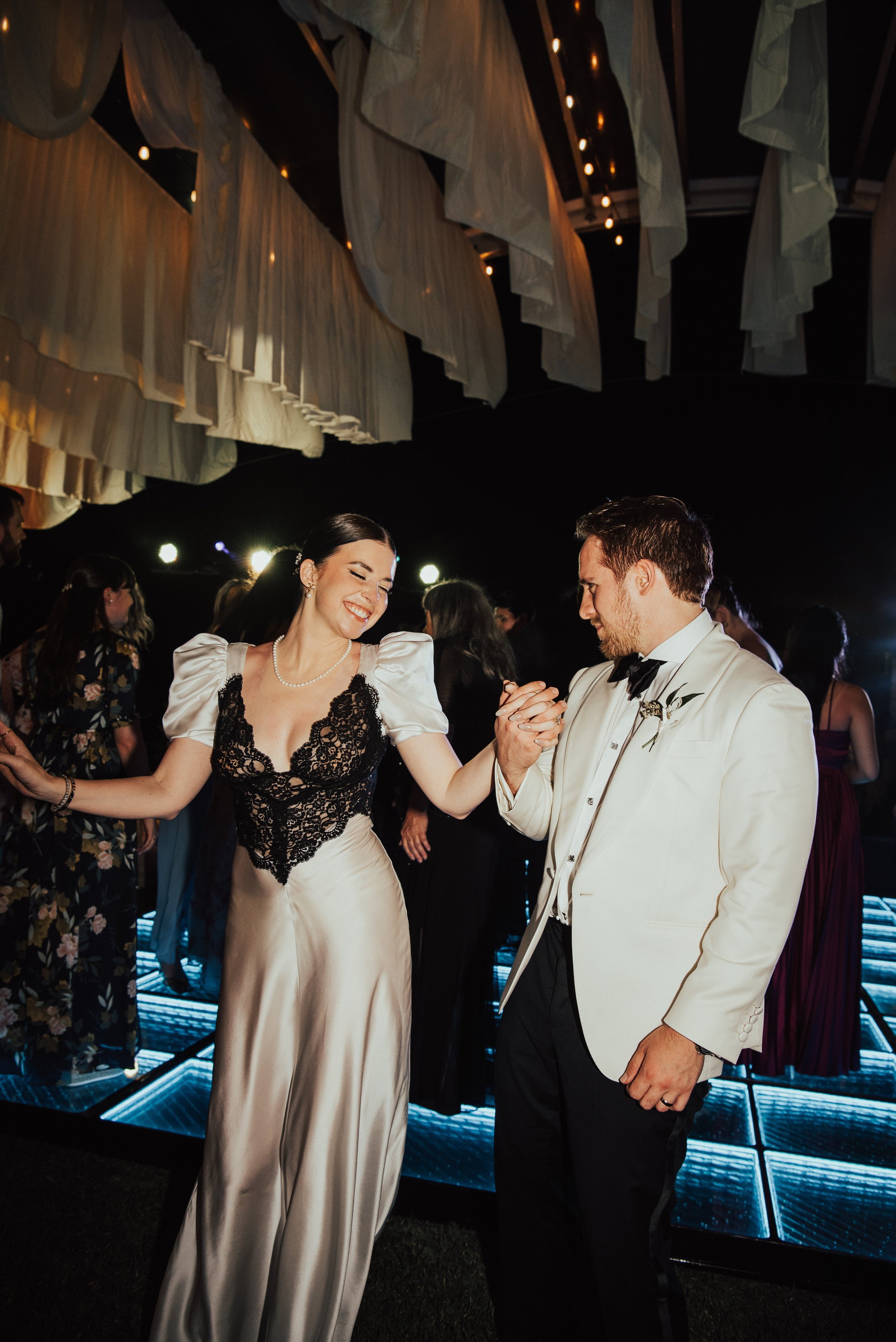 bride smiling with eyes close and groom looks at her and holds her hand
