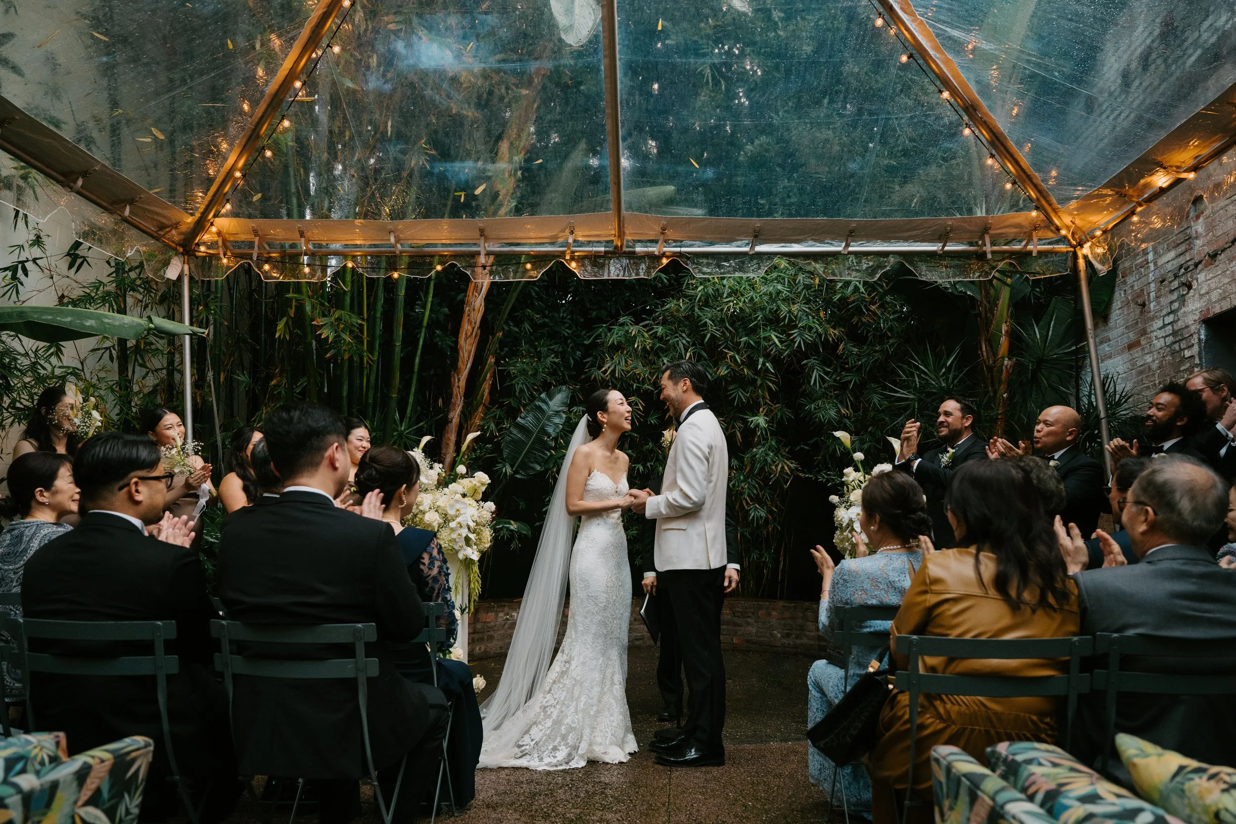 bride and groom standing at the front of their  ceremony holding hands and laughing as guest look on