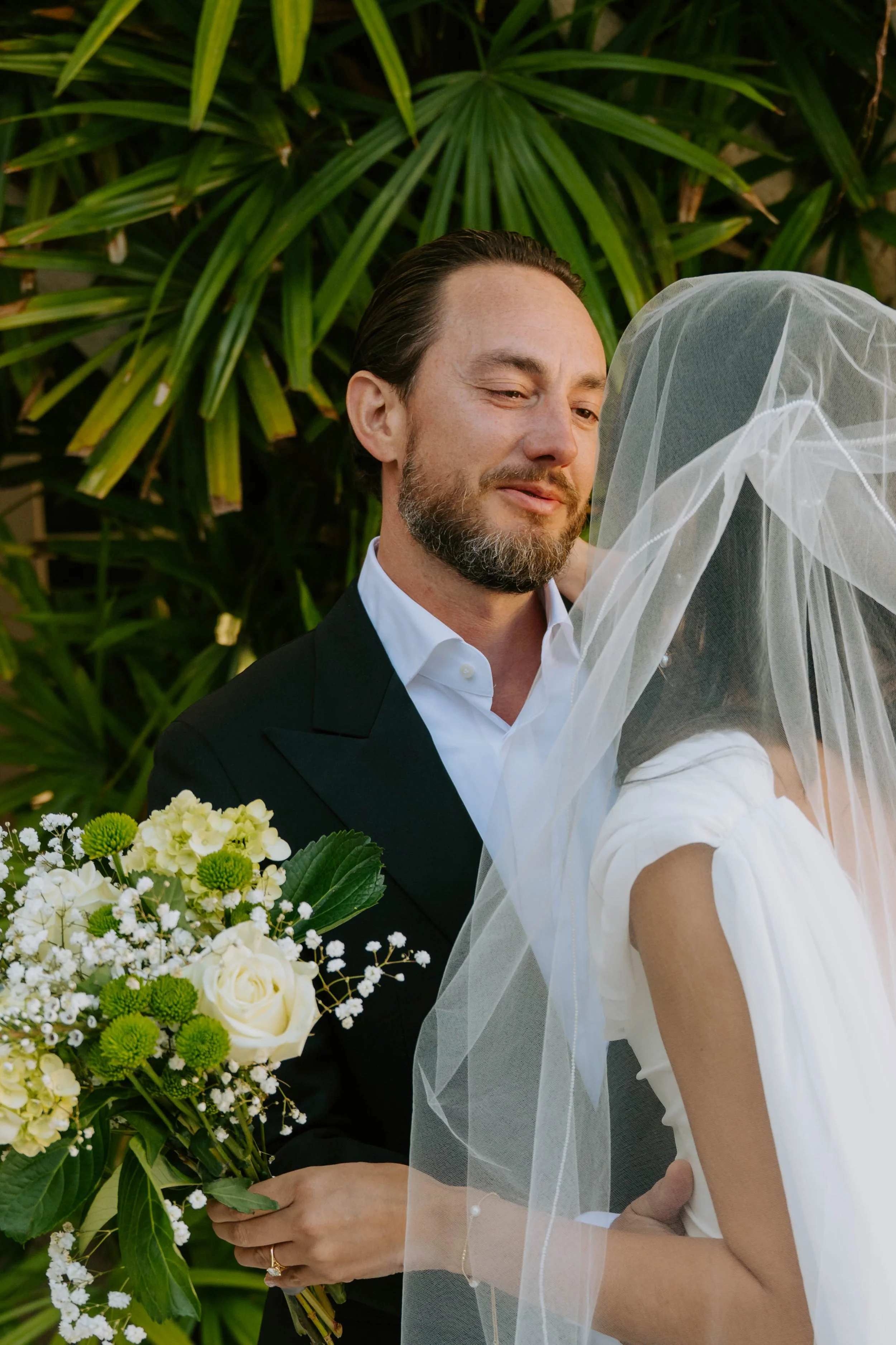 groom looking into the eyes of his bride with greenery in the background