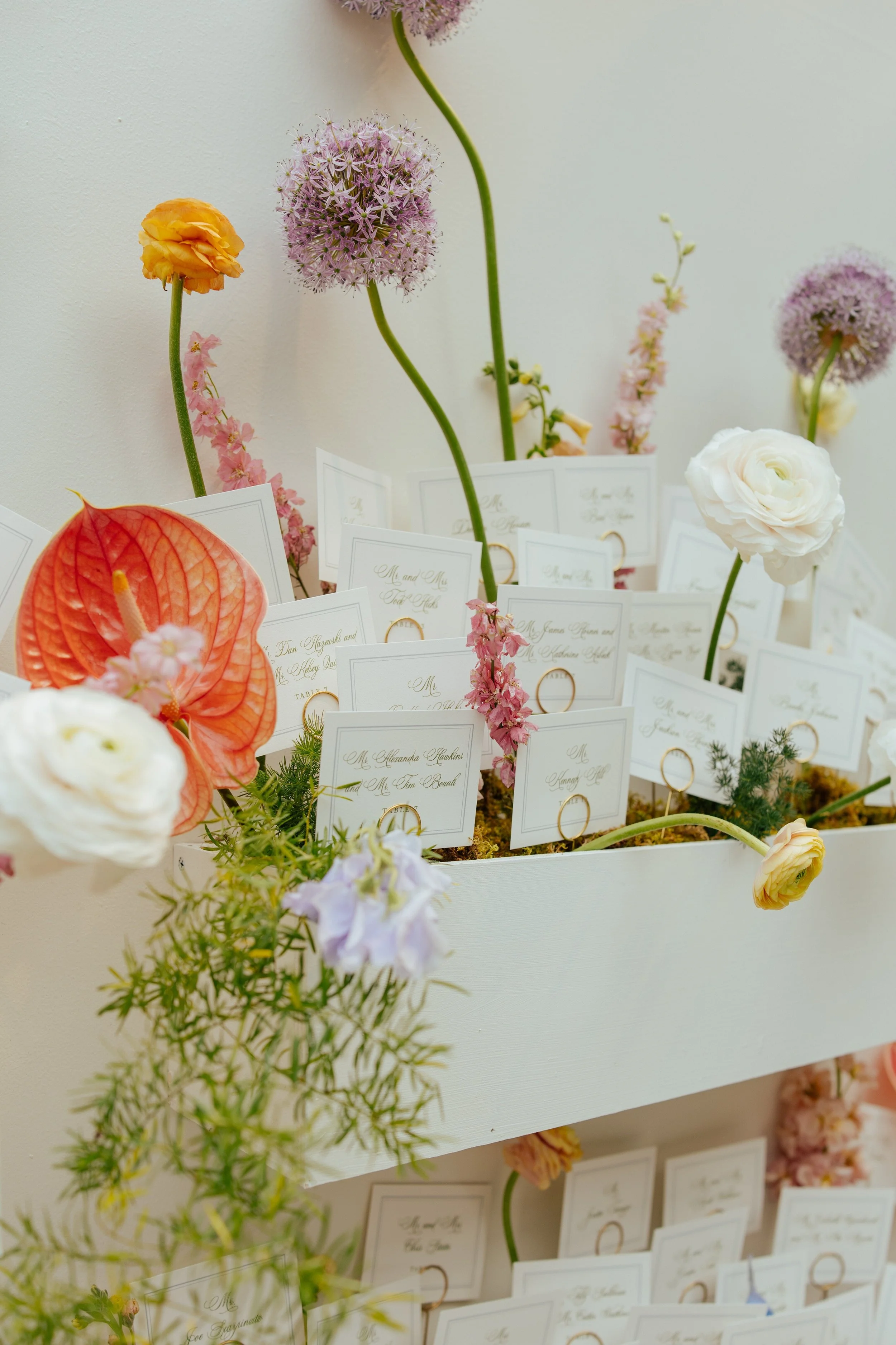 close up on wedding guest seat cards with brightly color florals