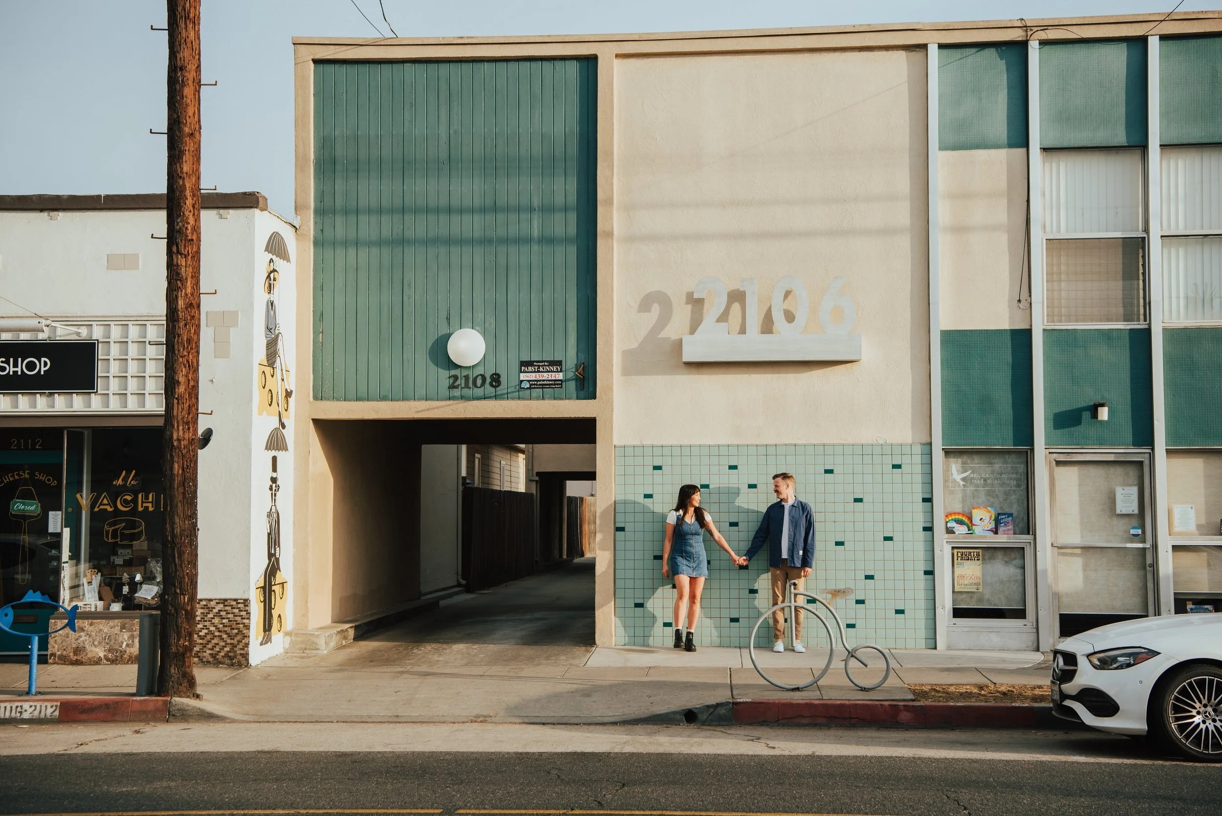 Wide shot of couple holding hands looking at each other on the sidewalk in Long beach California
